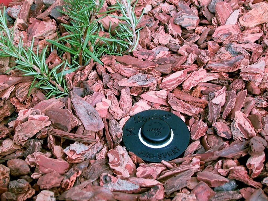 A sprinkler is sitting on top of a pile of wood chips.