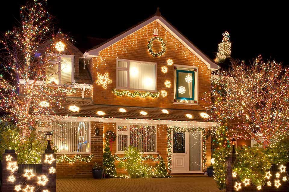 a house is decorated with christmas lights and trees