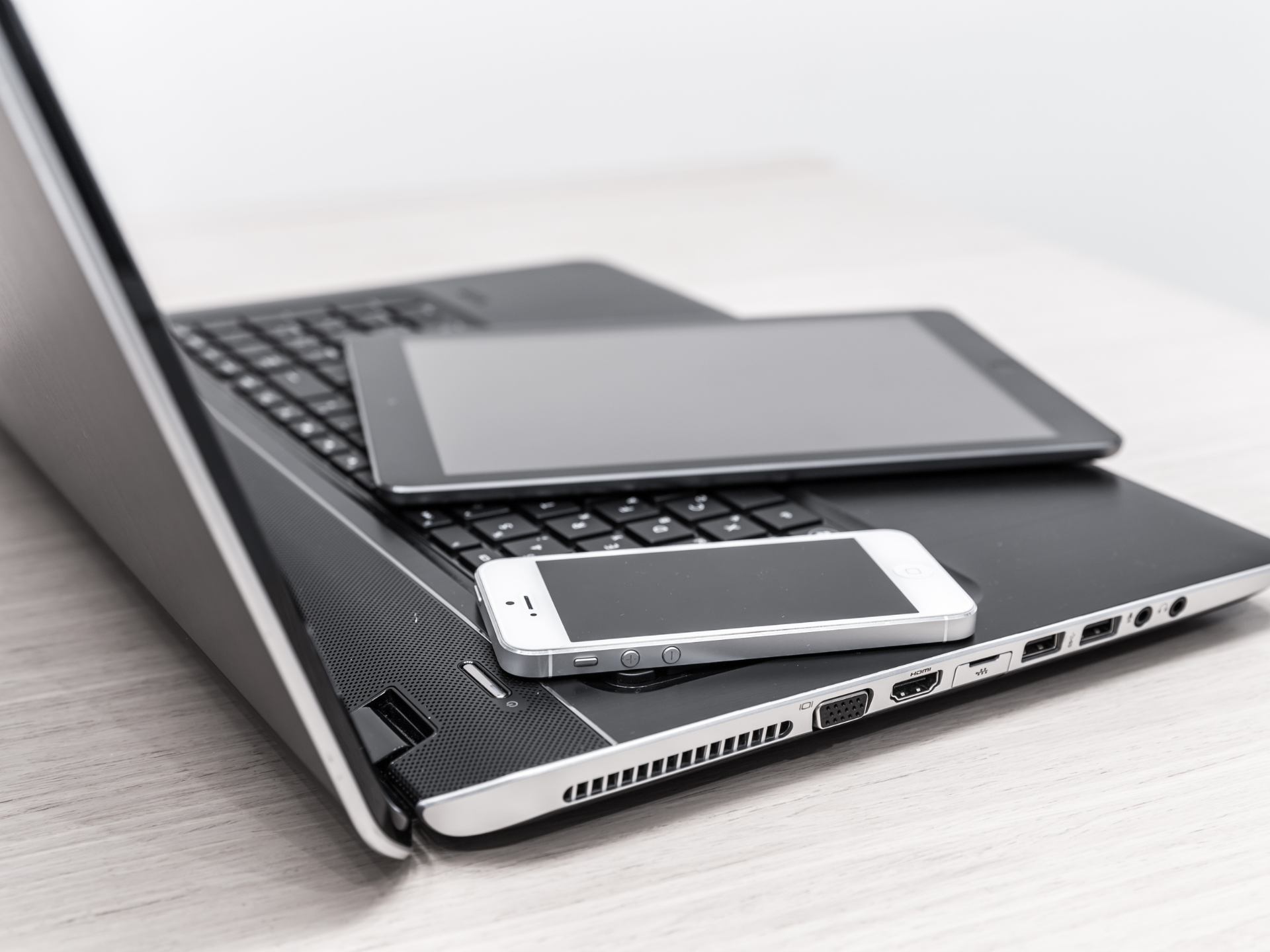 A cell phone is sitting on top of a laptop computer.