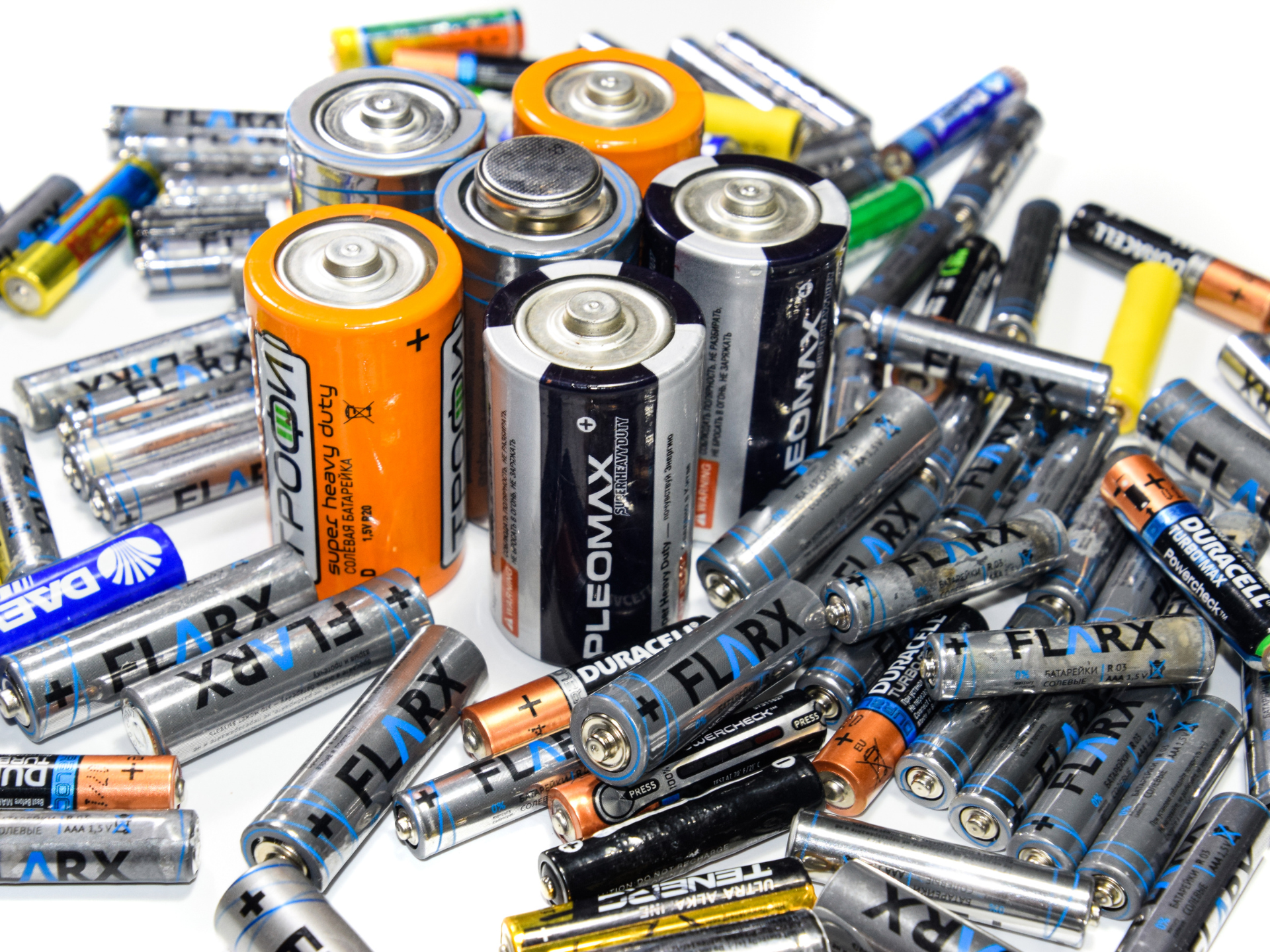 A pile of different types of batteries on a white background.