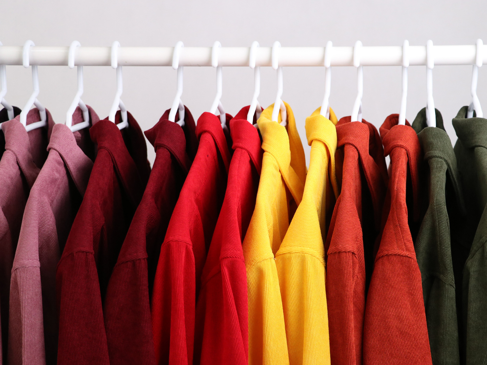 A row of colorful shirts hanging on a rack.