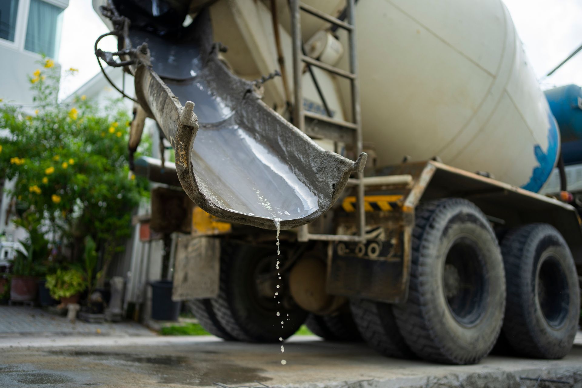 A concrete mixer truck is pouring concrete into the ground.