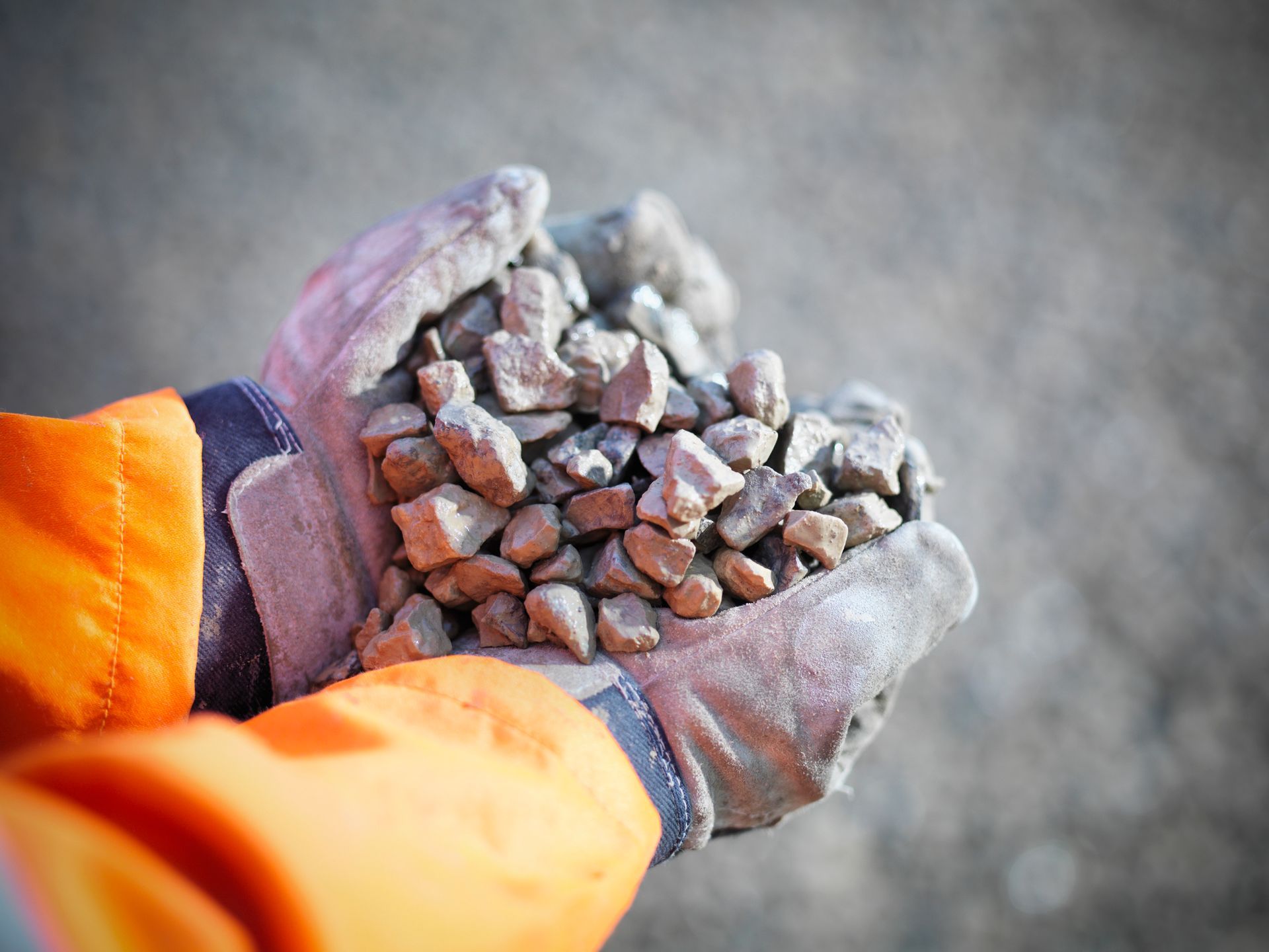 A person wearing gloves is holding a pile of rocks in their hands.