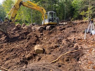 une excavatrice jaune creuse un trou dans la terre.