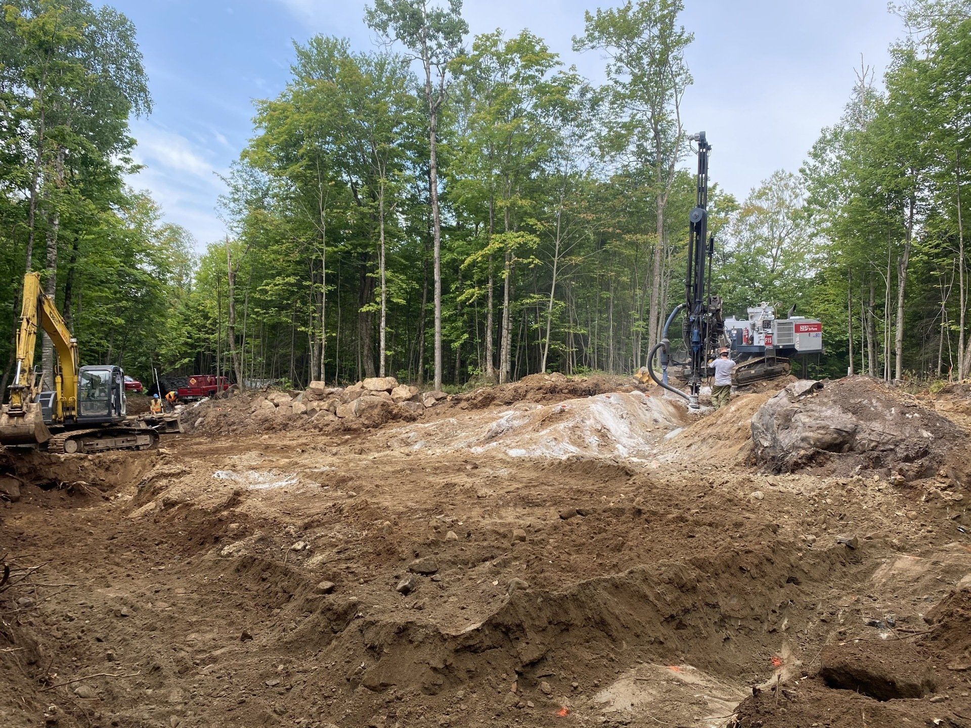 un chantier de construction avec beaucoup de terre et d arbres en arrière-plan.