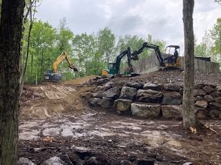 deux excavatrices travaillent sur une paroi rocheuse dans les bois.