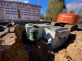 une pelle Hitachi est posée dans la terre devant une maison en construction.
