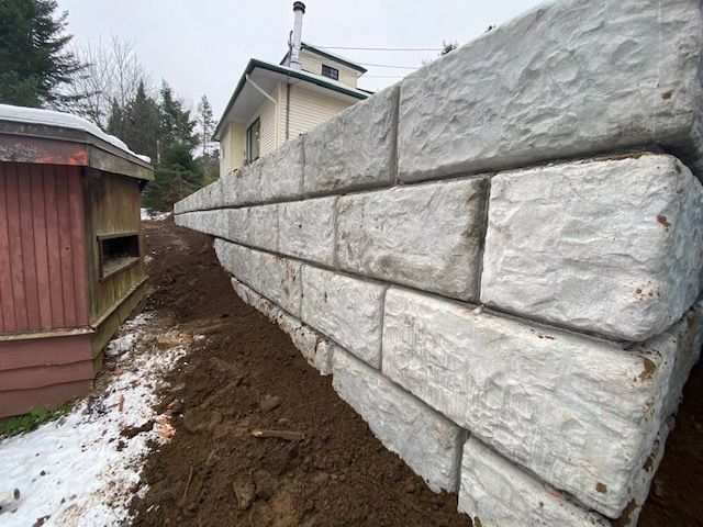 un grand mur de pierre est en construction devant une maison.