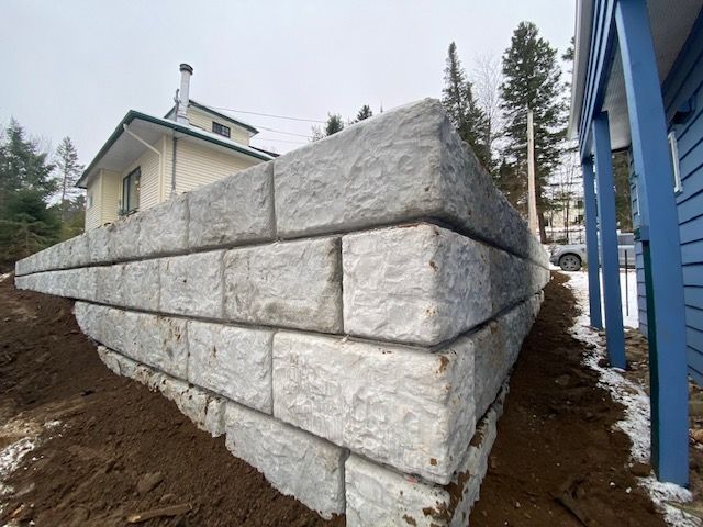 un grand mur de pierre est en construction devant une maison.