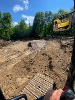 une personne conduit un bulldozer sur un chemin de terre.