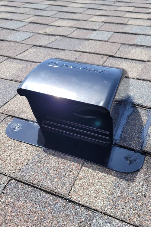Black roof vent on a brown shingled roof, sunny day.