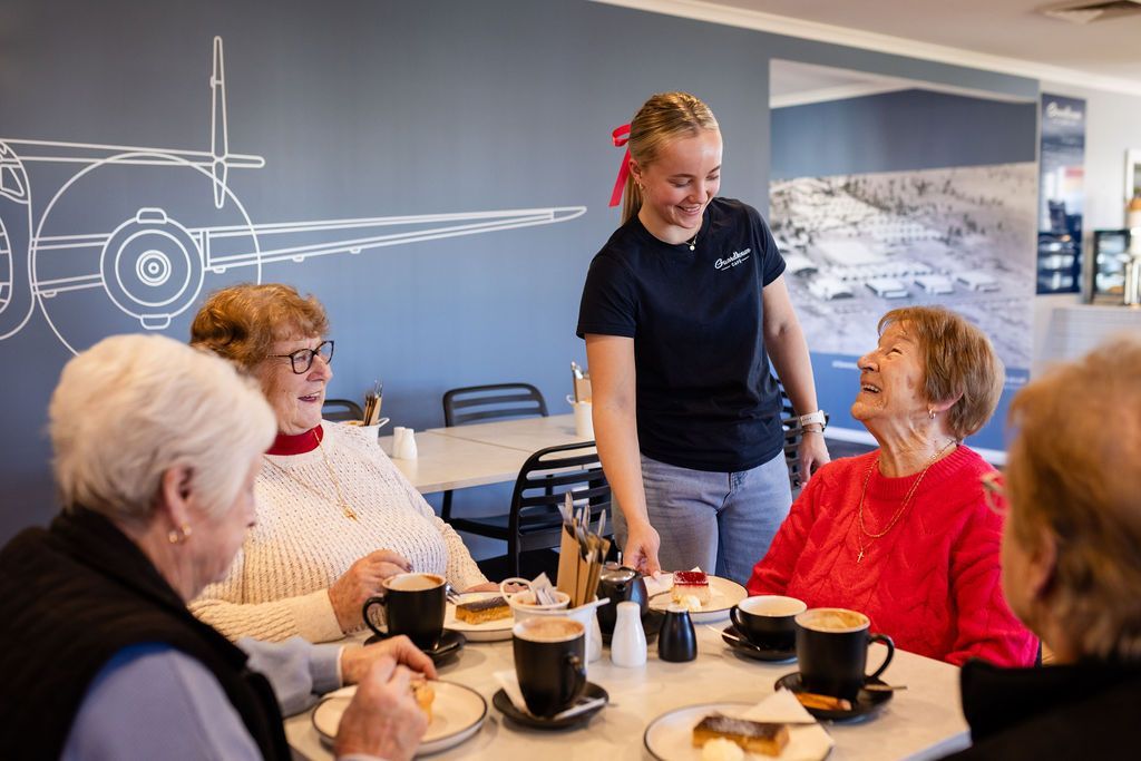 A woman is serving food to a group of women sitting at a table.