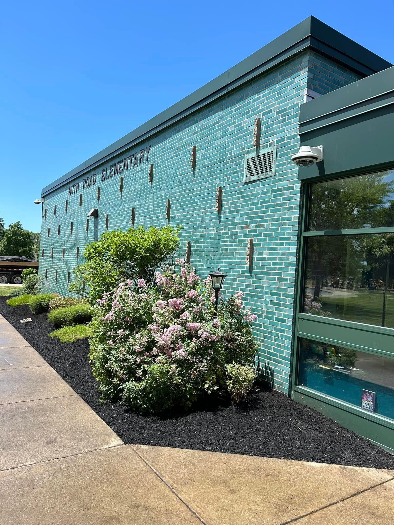 A large green building with a lot of windows and flowers in front of it.