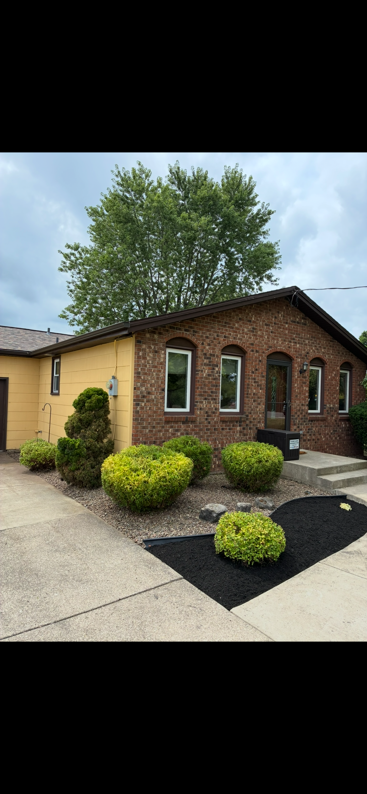 A fence surrounds a swimming pool with a blue cover on it.