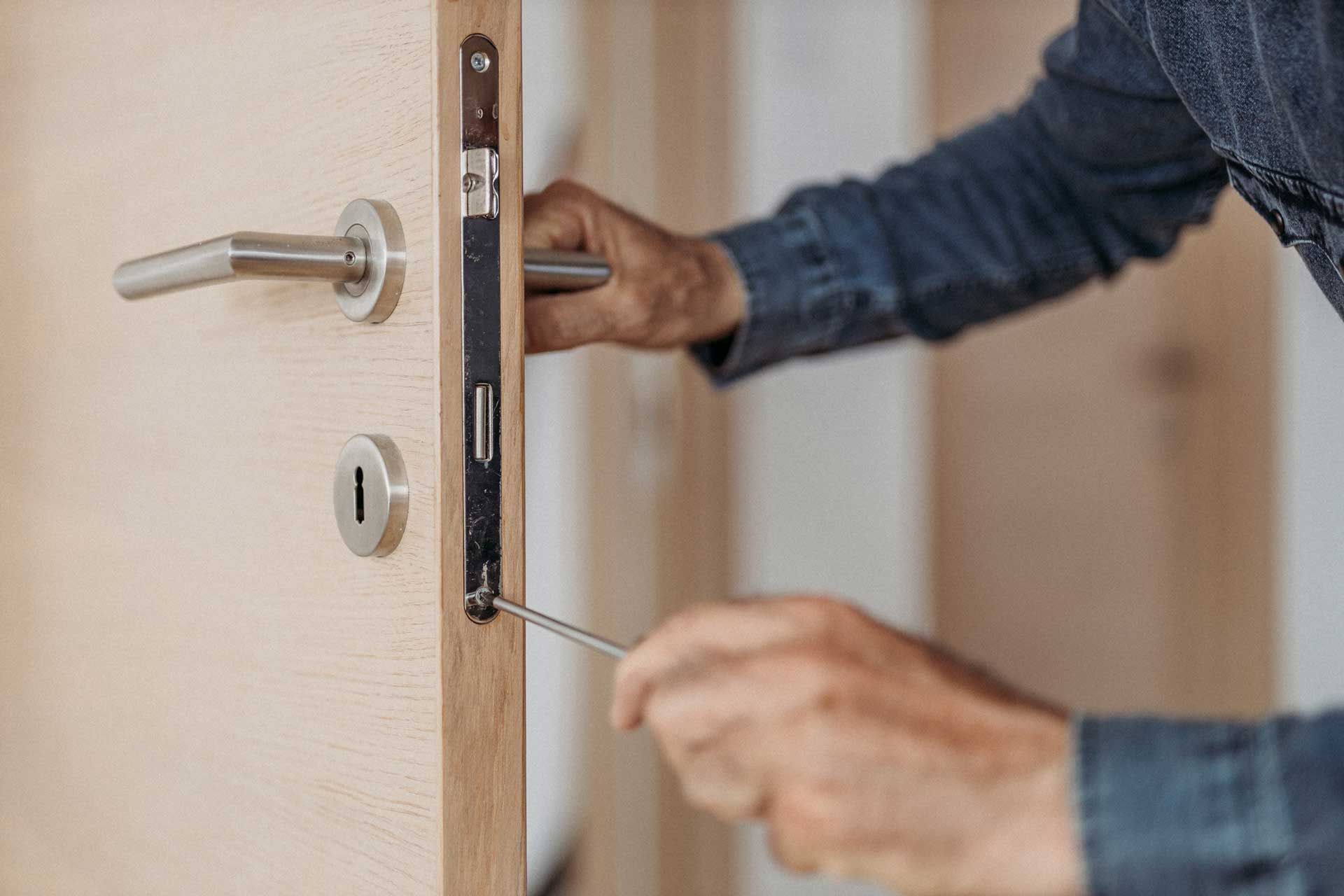 A professional 24-hour locksmith in Kannapolis, NC fixing a door lock with a screwdriver