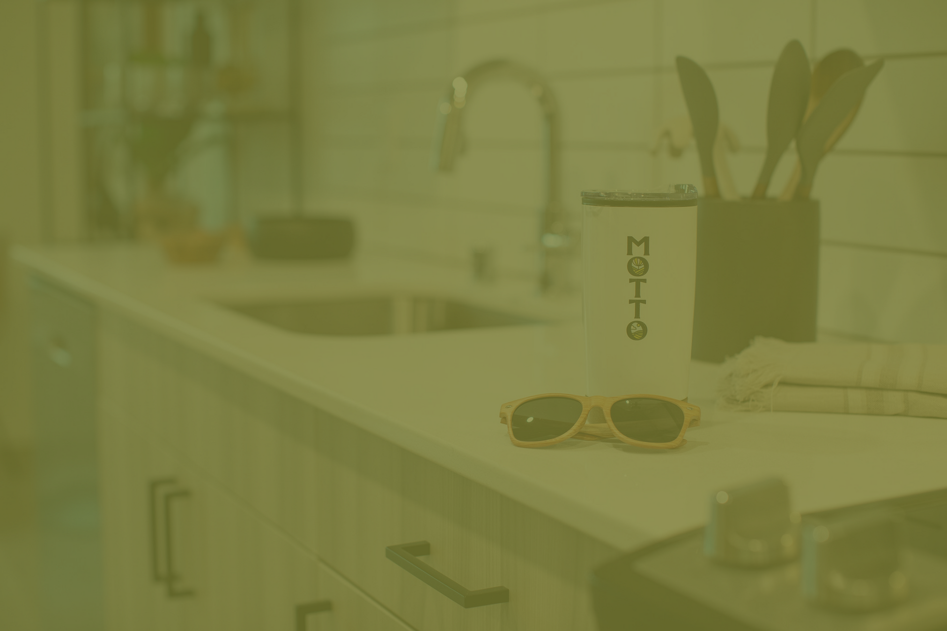 A pair of sunglasses is sitting on a kitchen counter next to a kitchen sink.