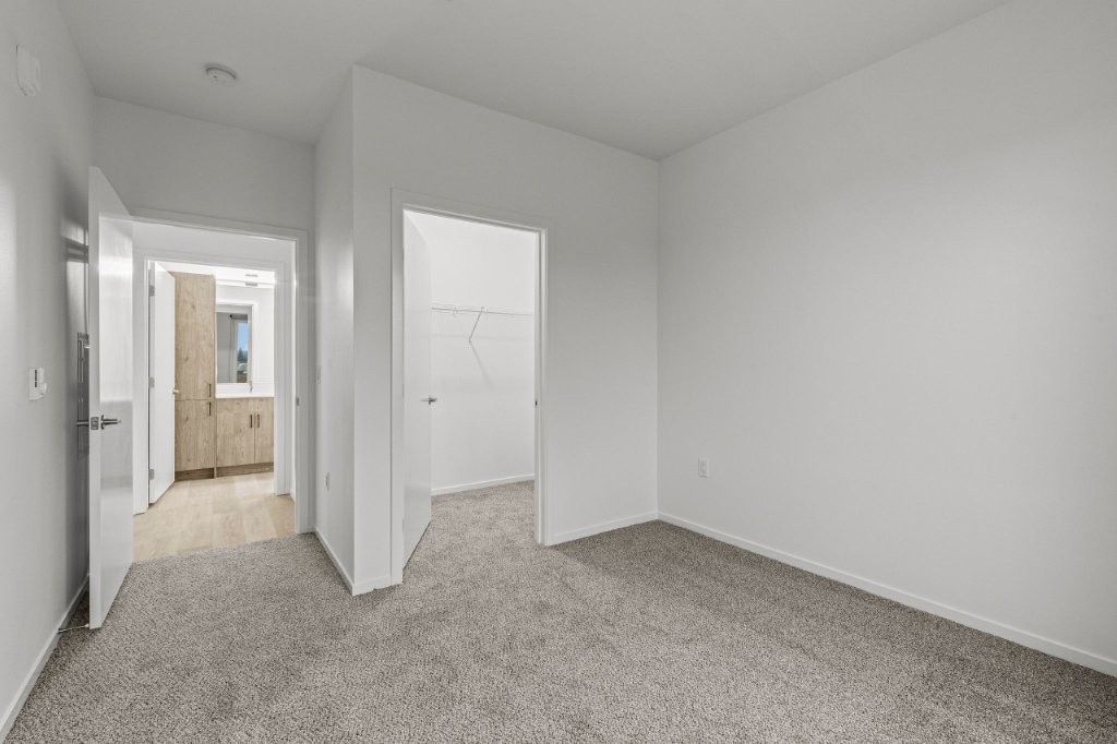 An empty room with a carpeted floor and white walls.