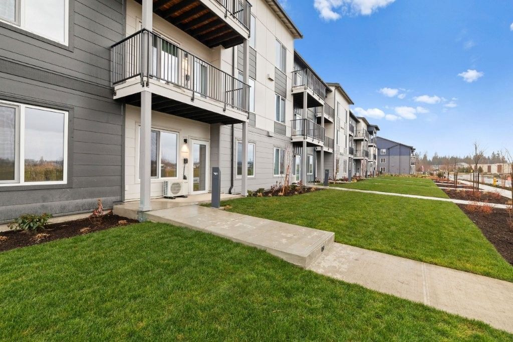 A large apartment building with a lush green lawn in front of it.