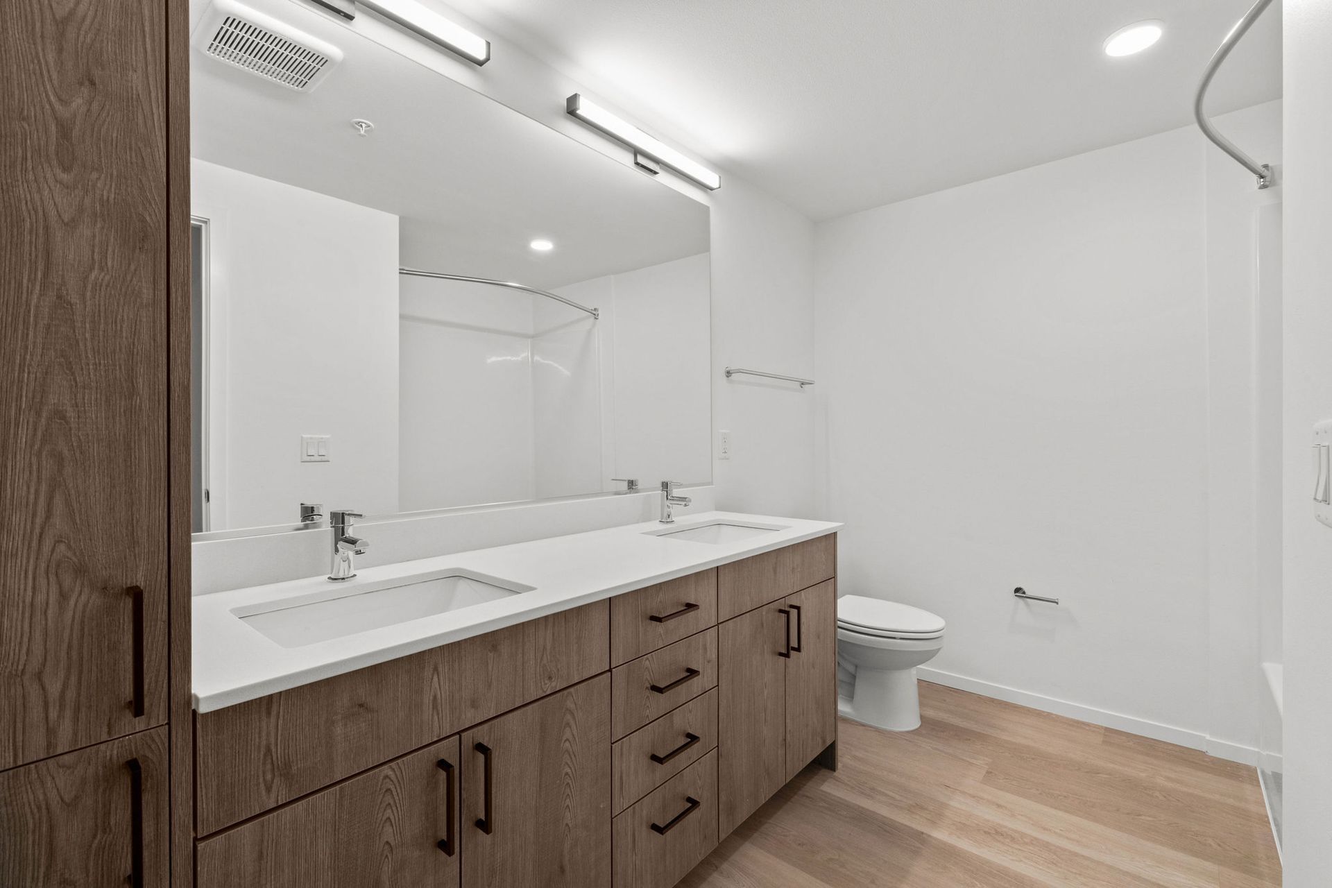 A bathroom with two sinks , a toilet , and a large mirror.