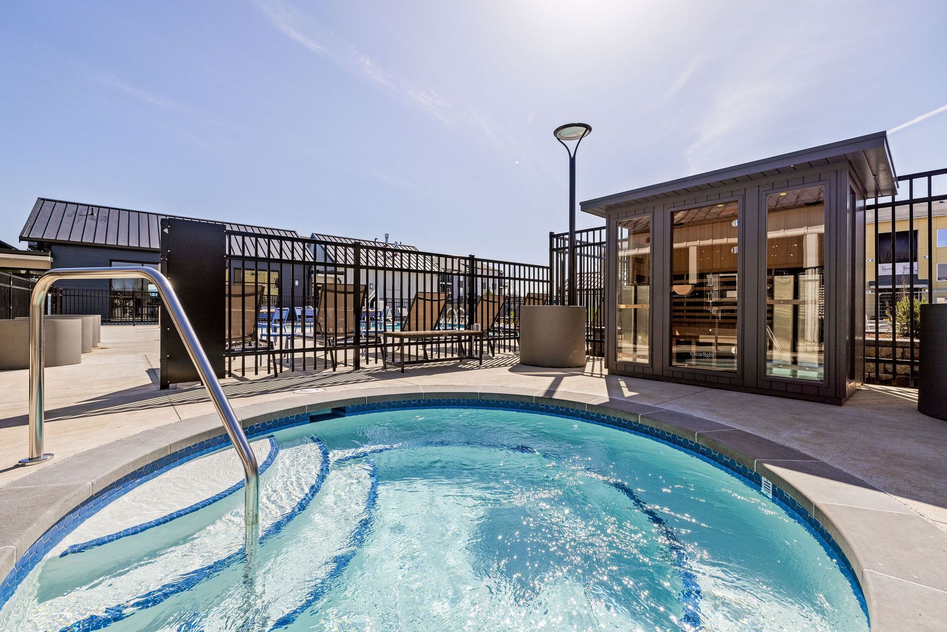 A large swimming pool with stairs leading to it is surrounded by a fence.