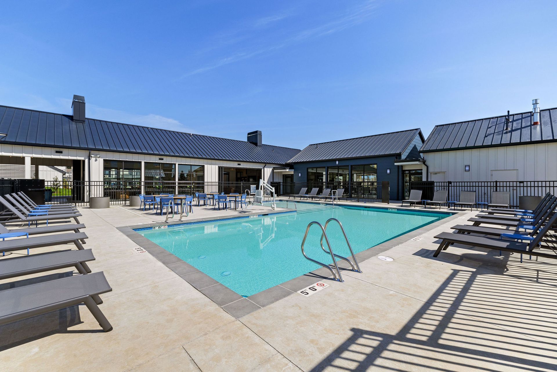 A large swimming pool surrounded by chairs and a building.