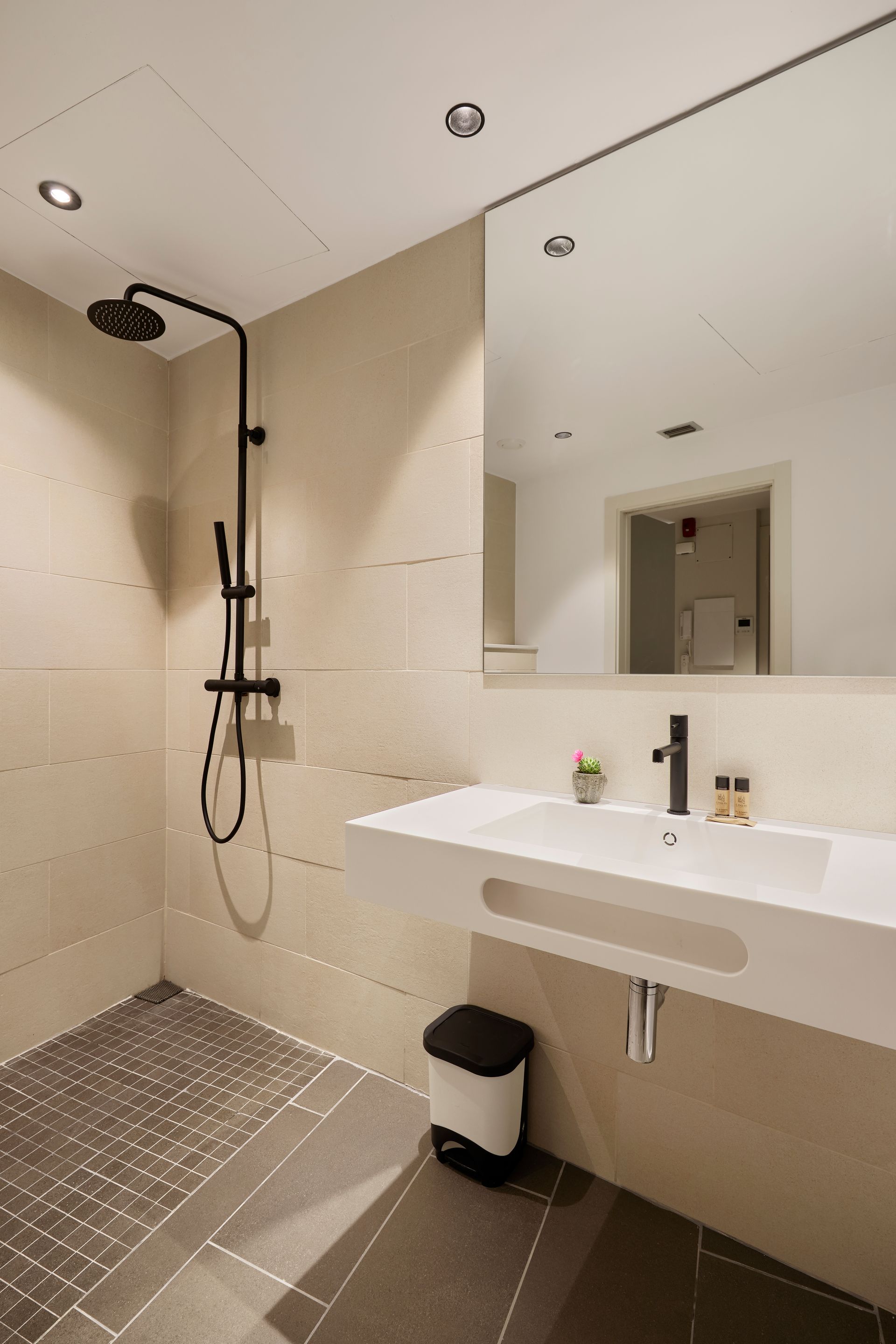 A bathroom with a sink , mirror and shower.