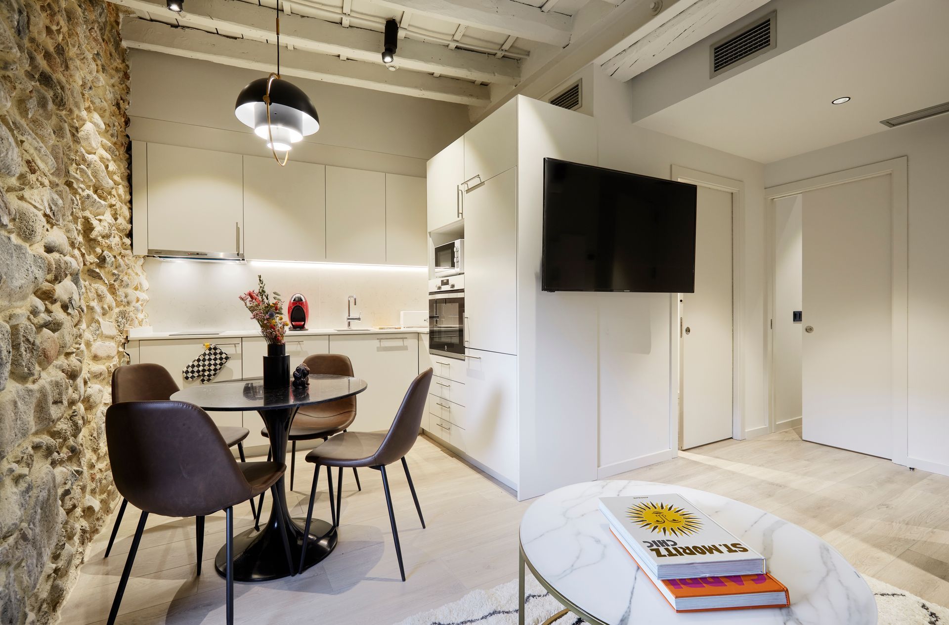 A living room with a dining table and chairs and a flat screen tv.