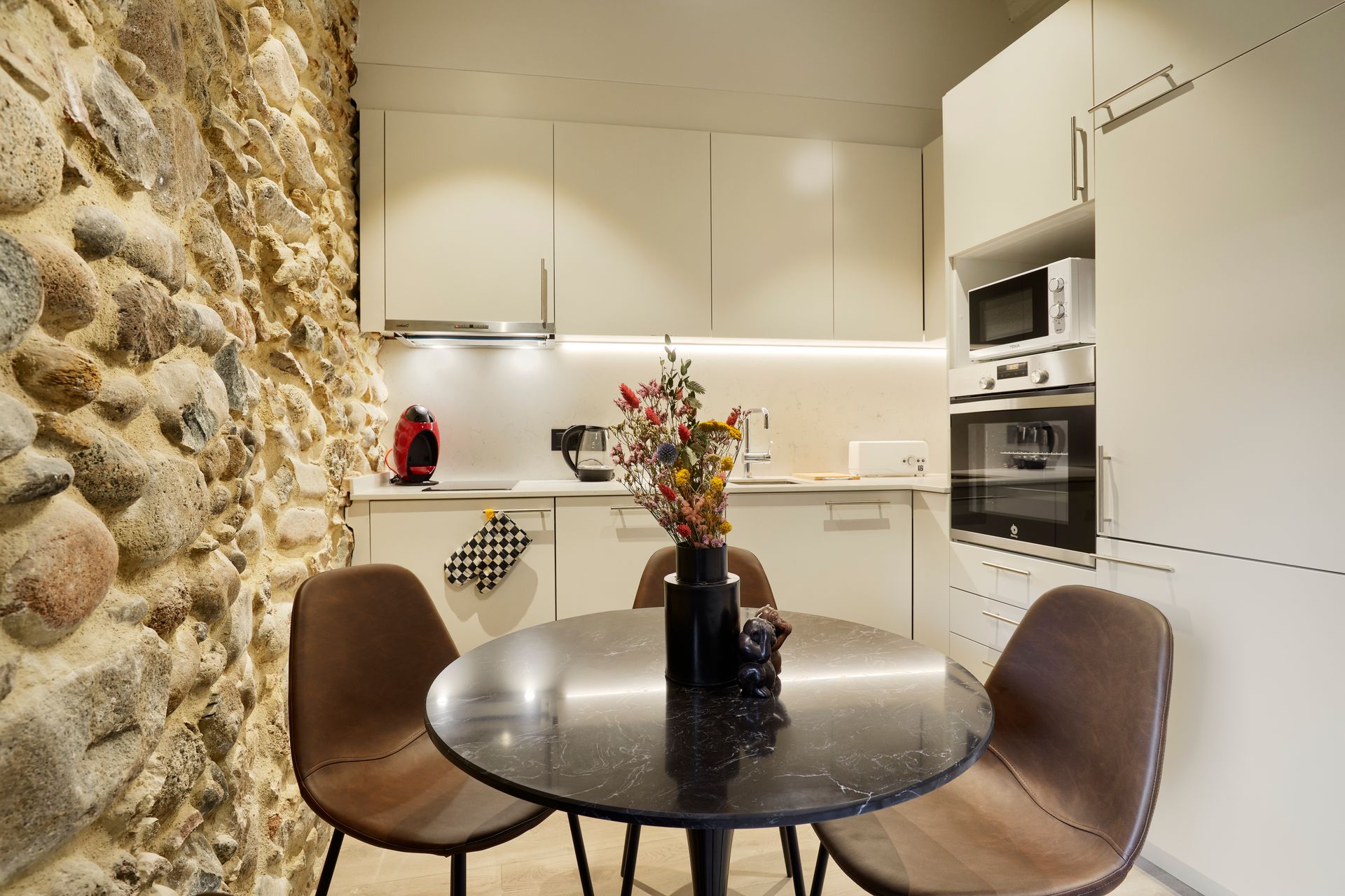 A kitchen with a table and chairs and a stone wall
