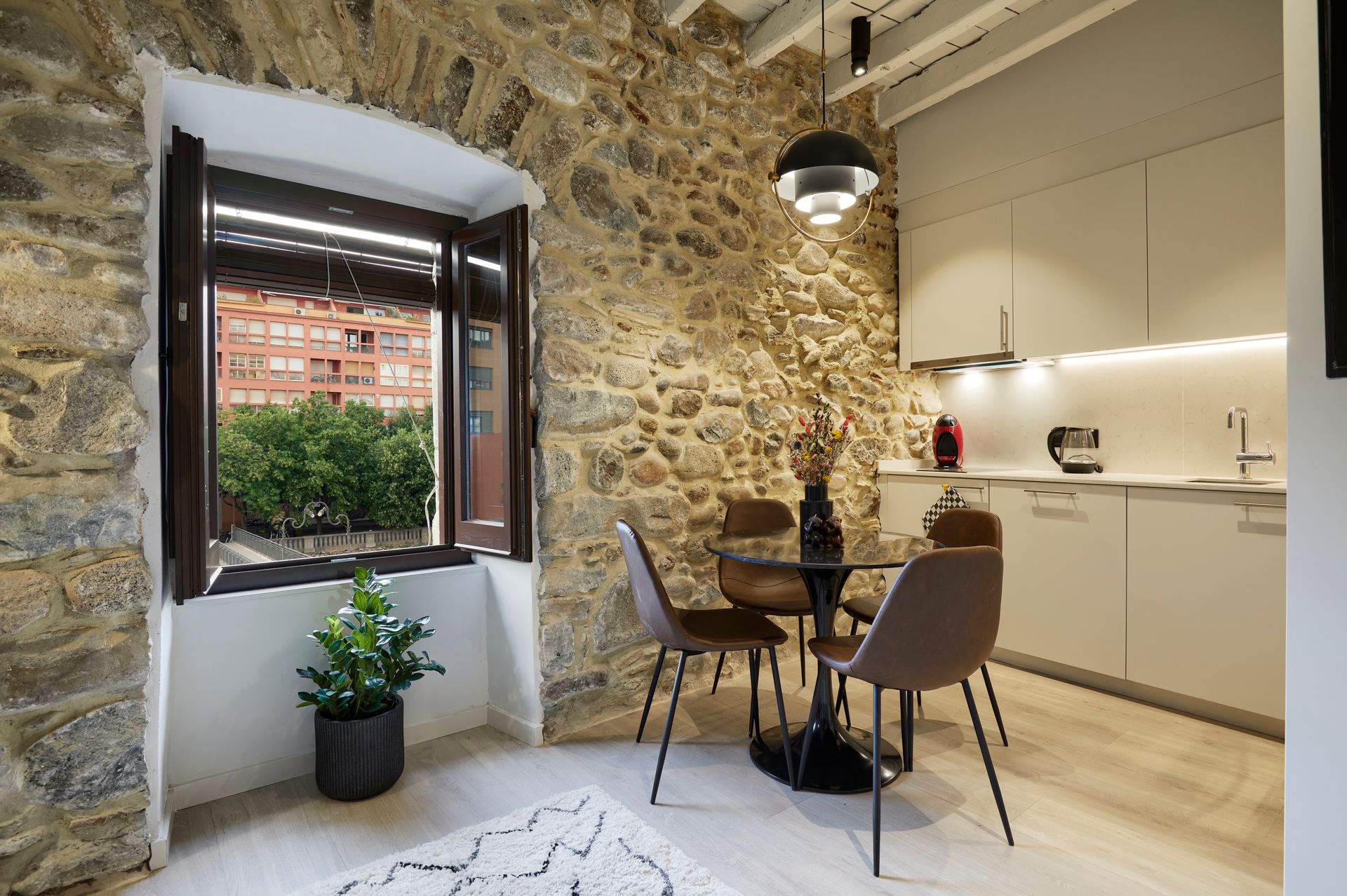 A kitchen with a table and chairs in front of a stone wall.