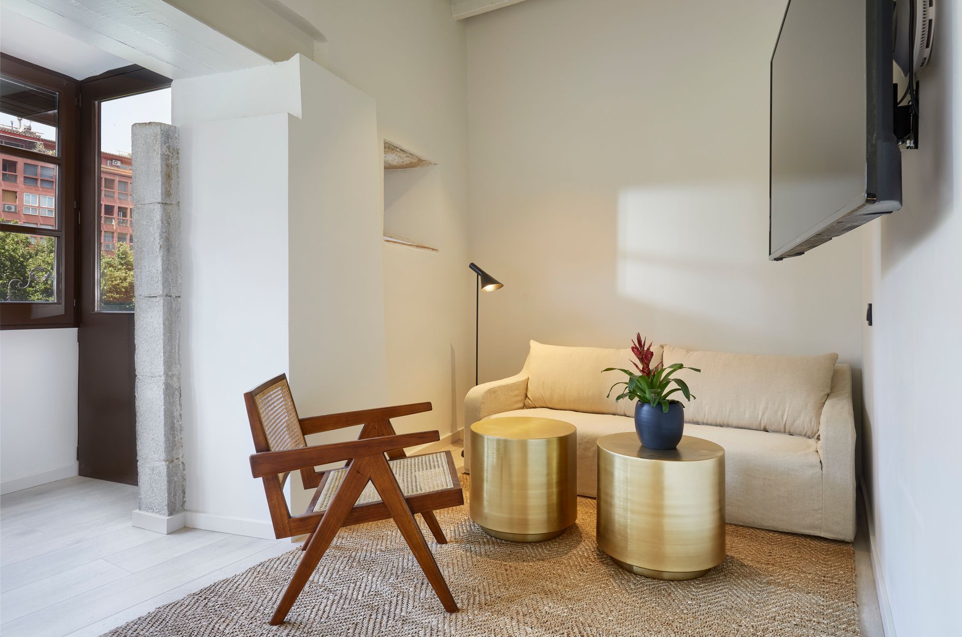 A living room with a couch , chair , tables and a flat screen tv.