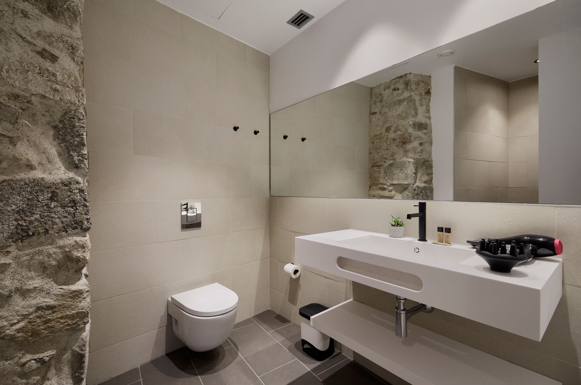 A bathroom with a toilet , sink and mirror.