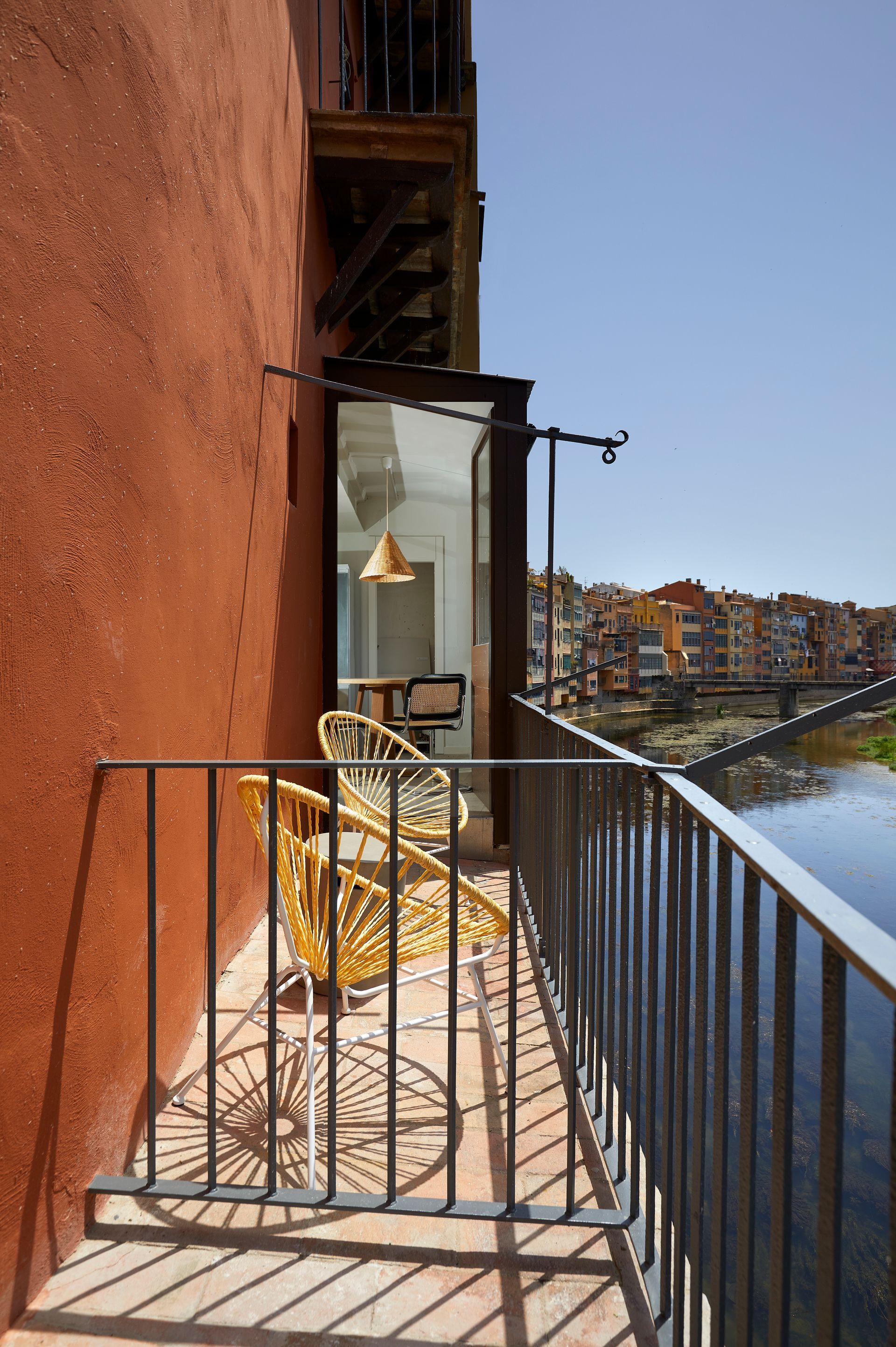 A balcony with chairs and a table overlooking a river.