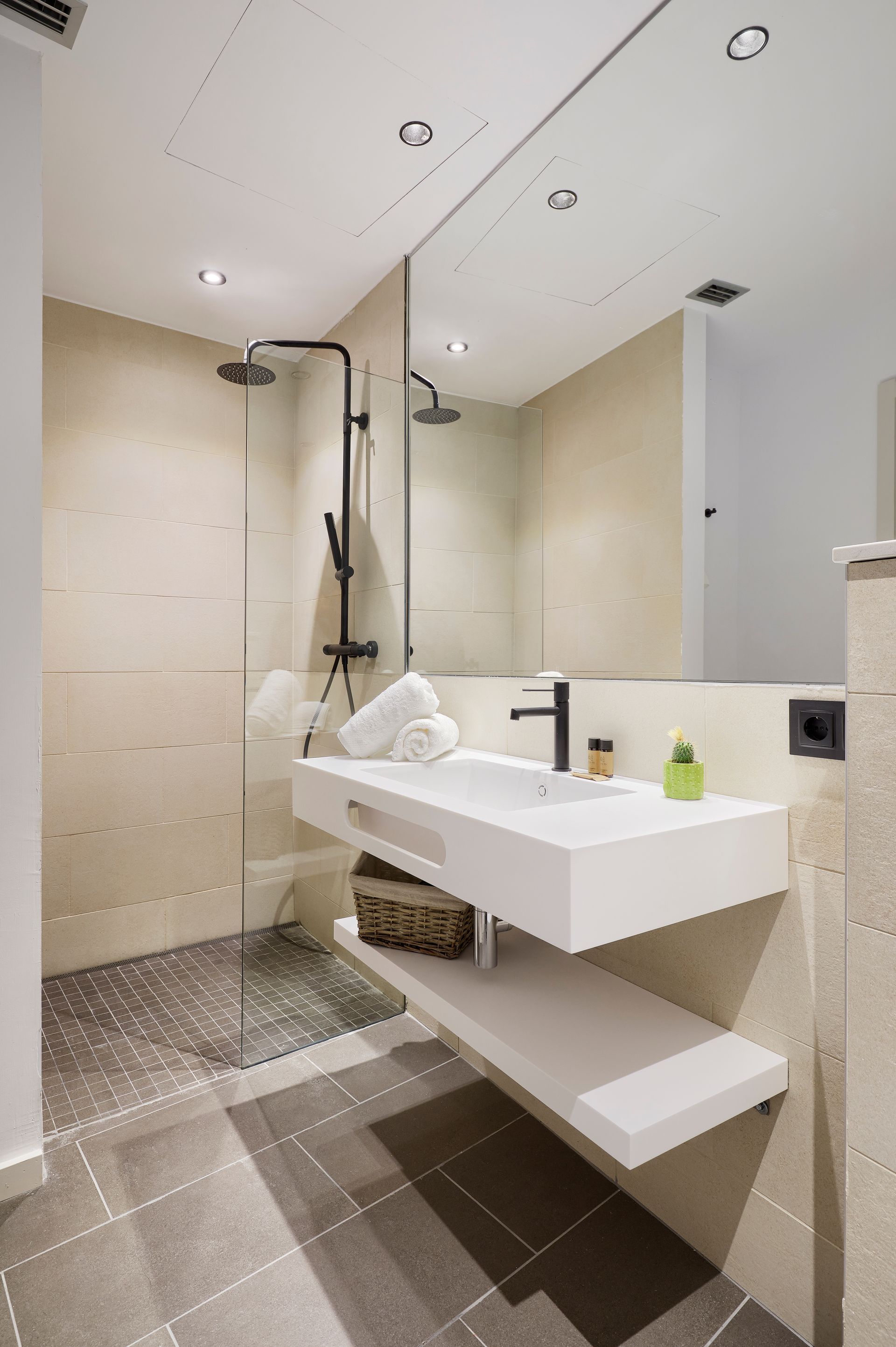 A bathroom with a sink , mirror and walk in shower.