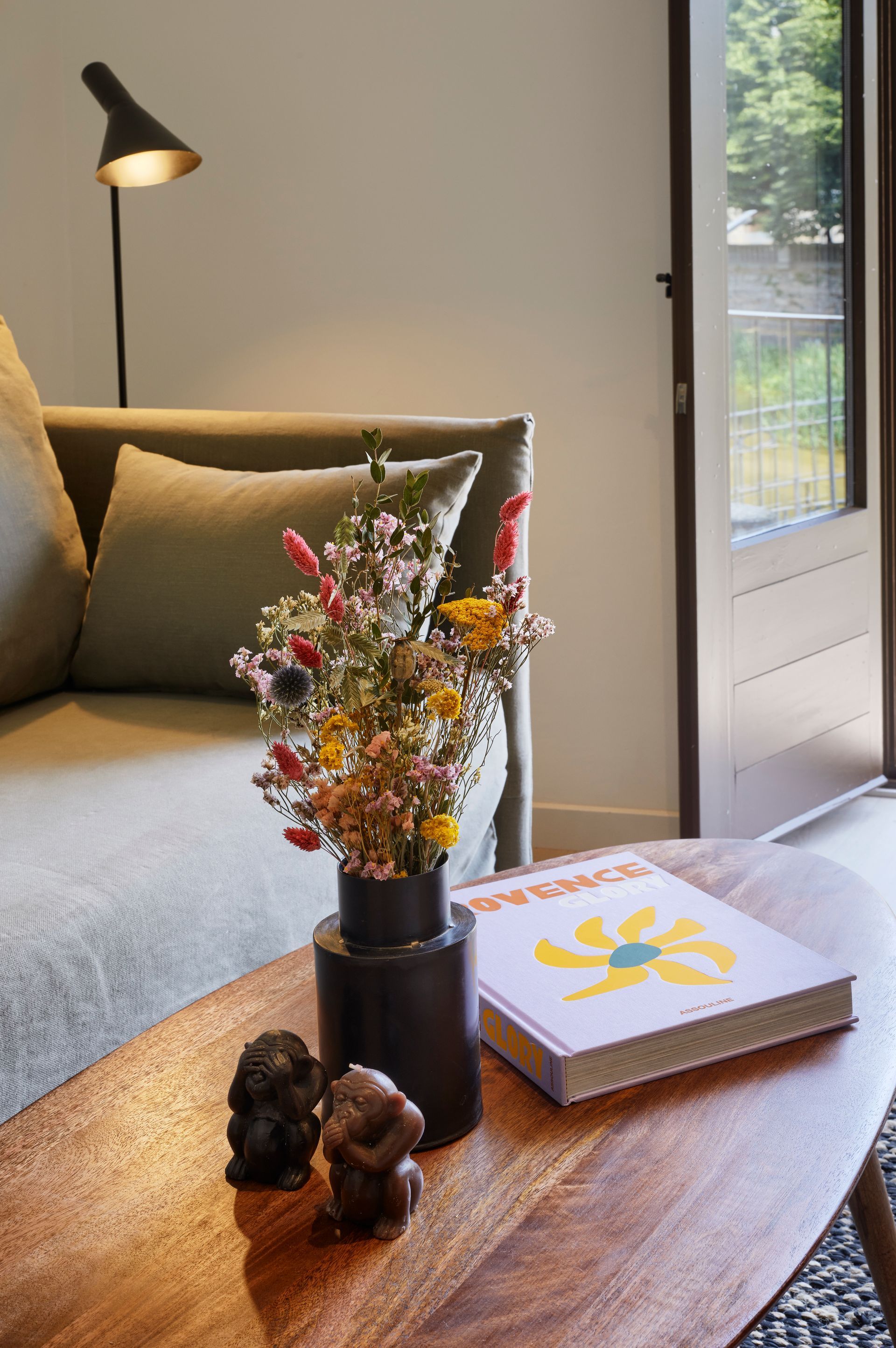 A table with a vase of flowers and a book on it in a living room.