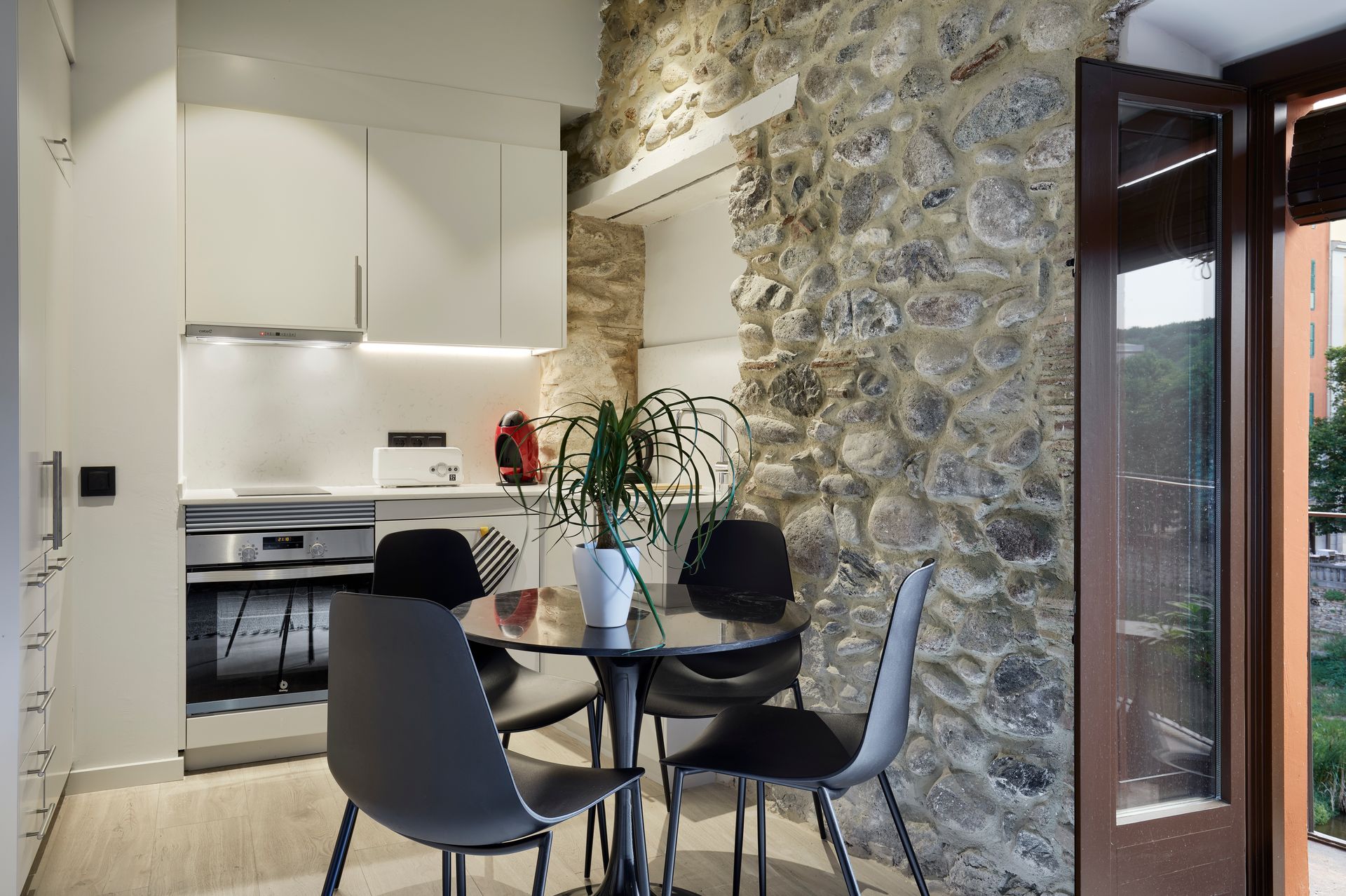 A kitchen with a table and chairs and a stone wall