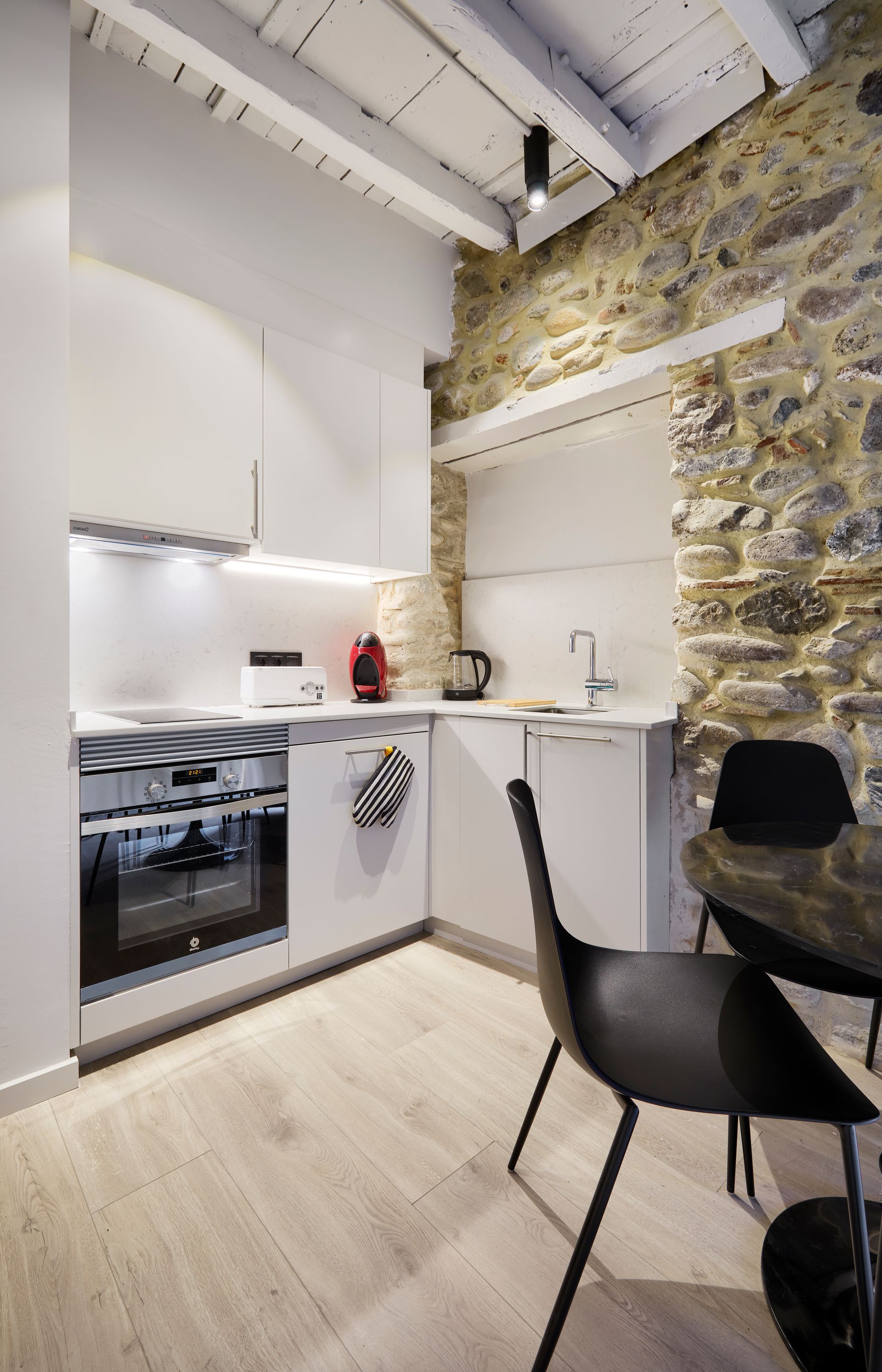A kitchen with a table and chairs and a stone wall