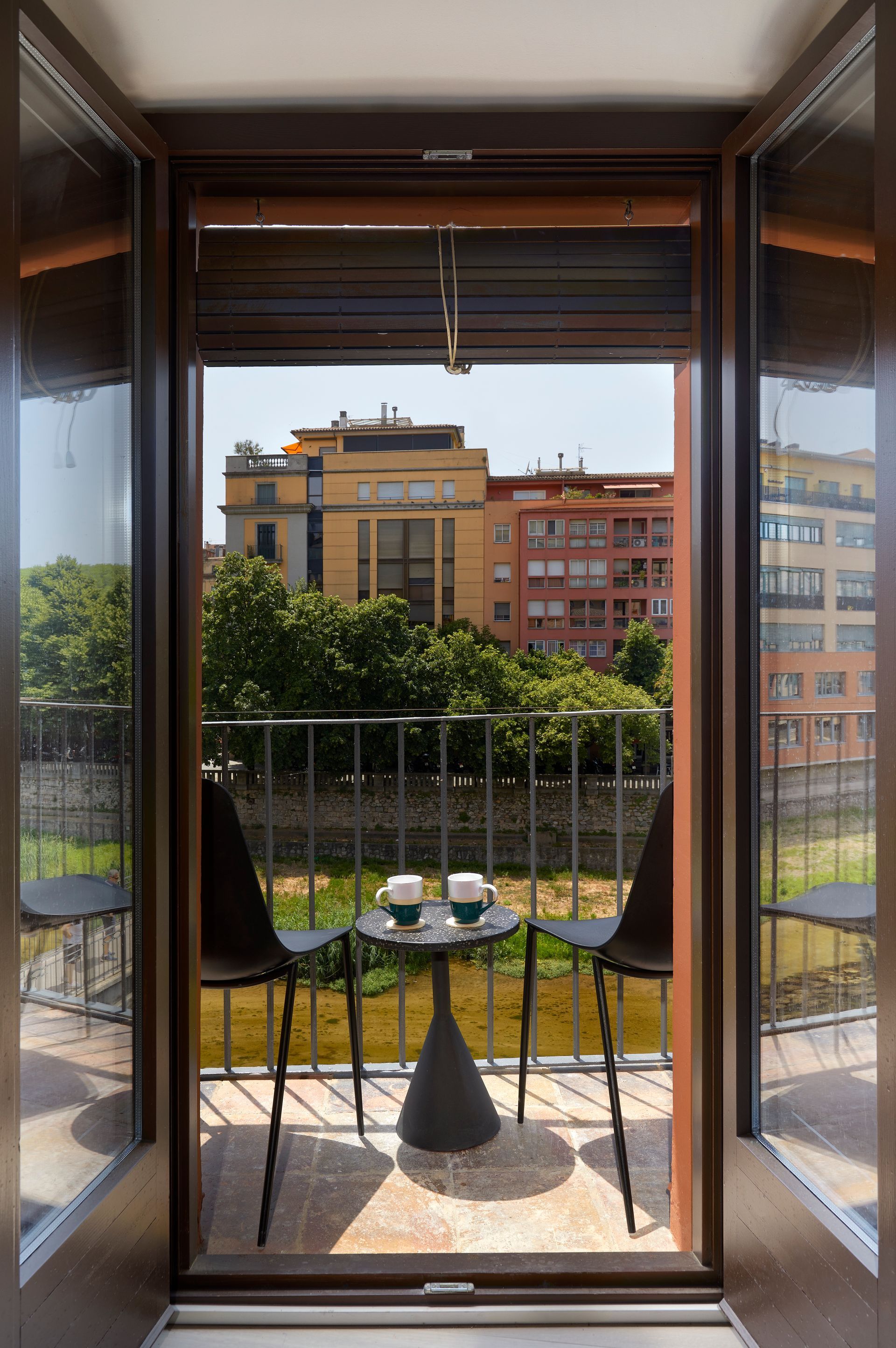 A balcony with a table and chairs overlooking a river.