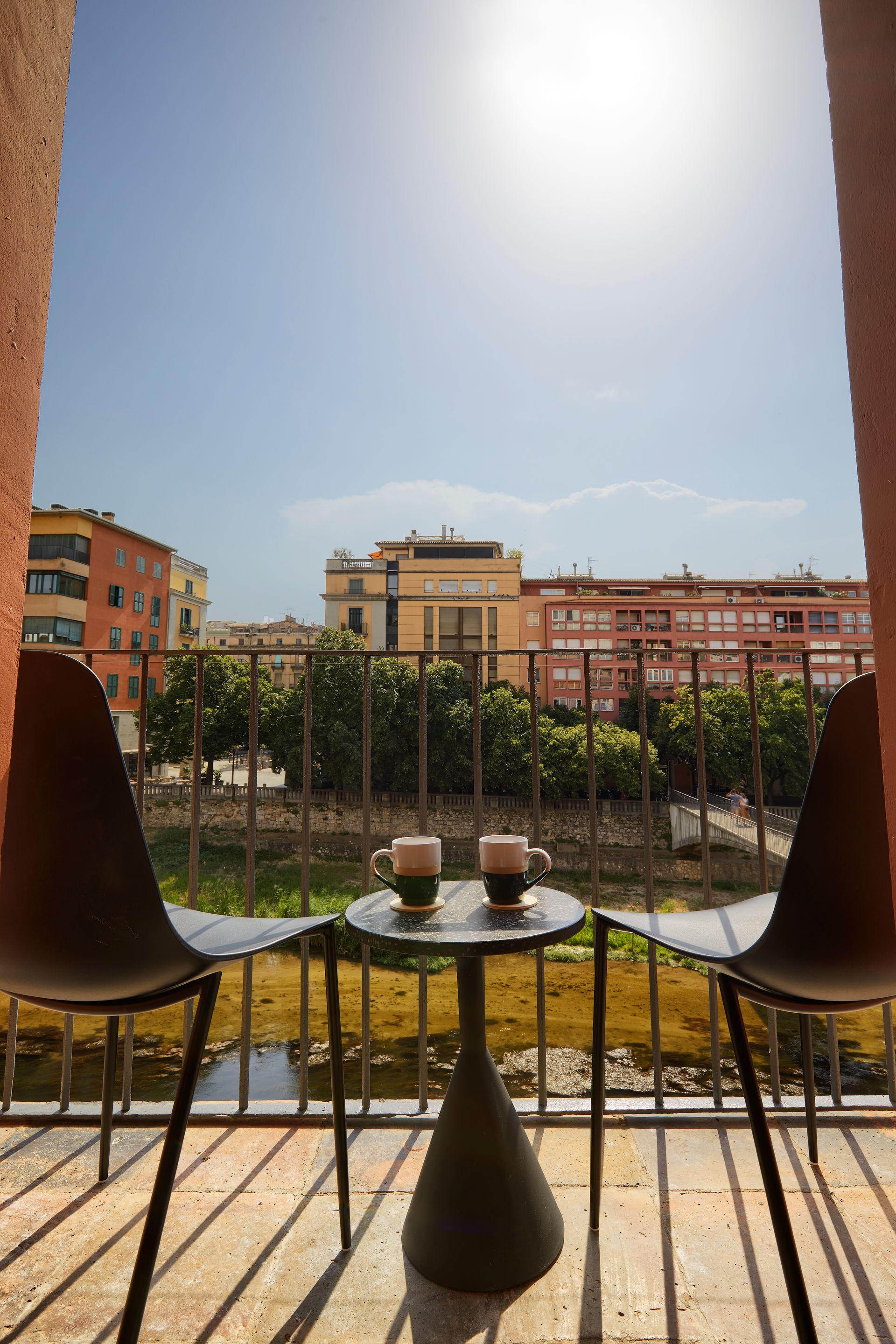 A balcony with two chairs and a table with two cups of coffee on it.