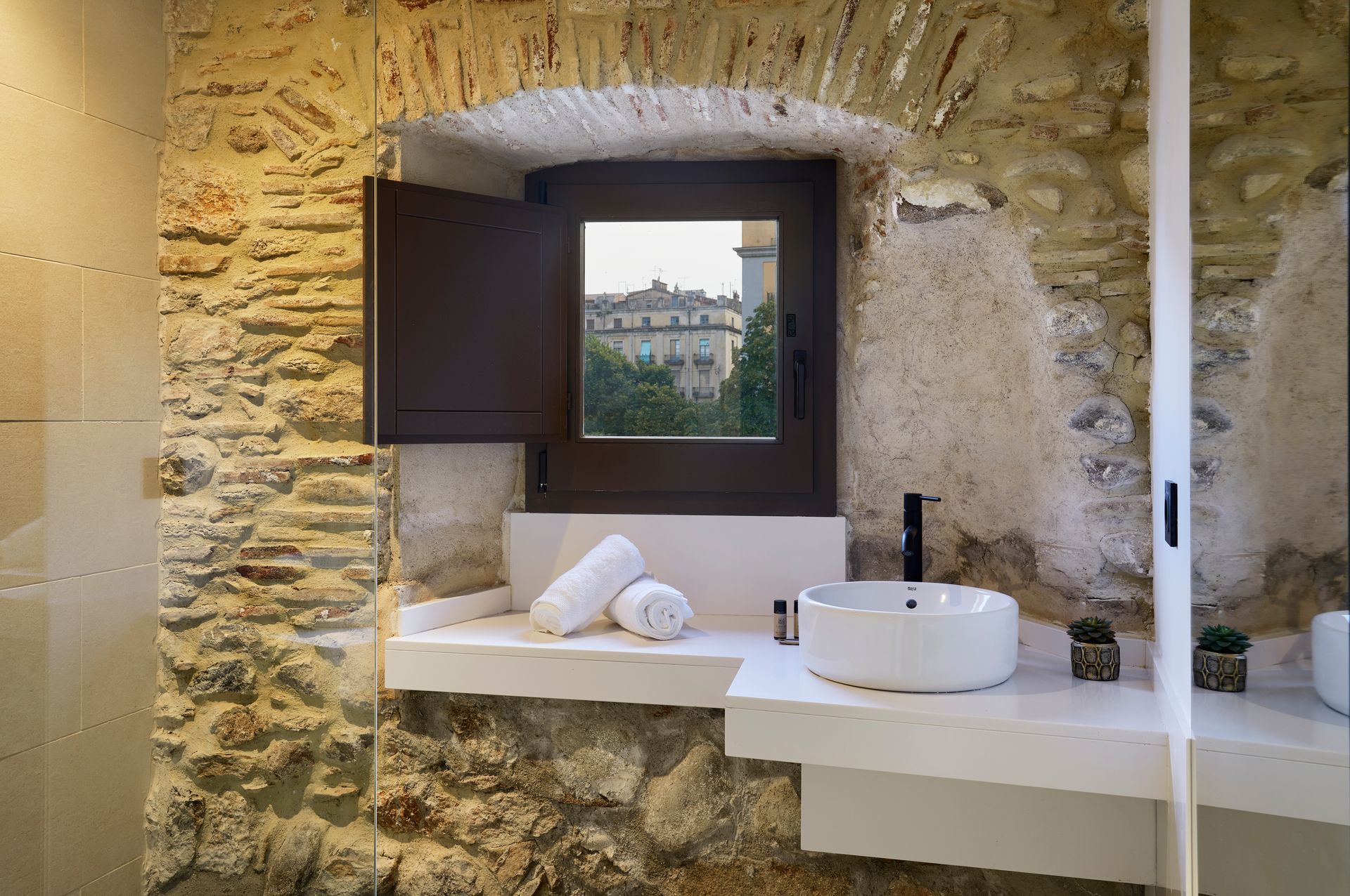 A bathroom with a sink , mirror and window.