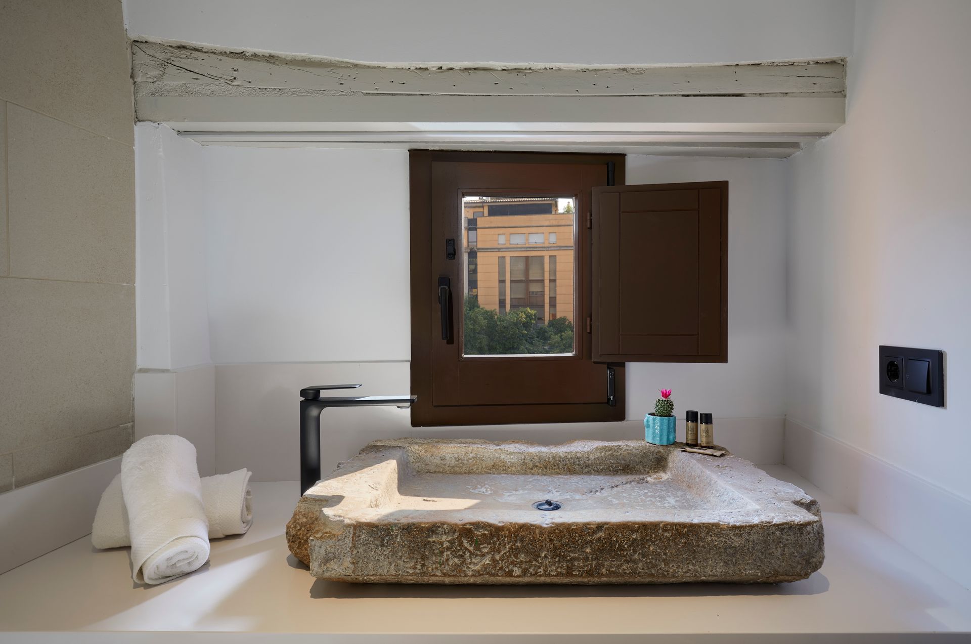 A bathroom with a large stone sink and a window