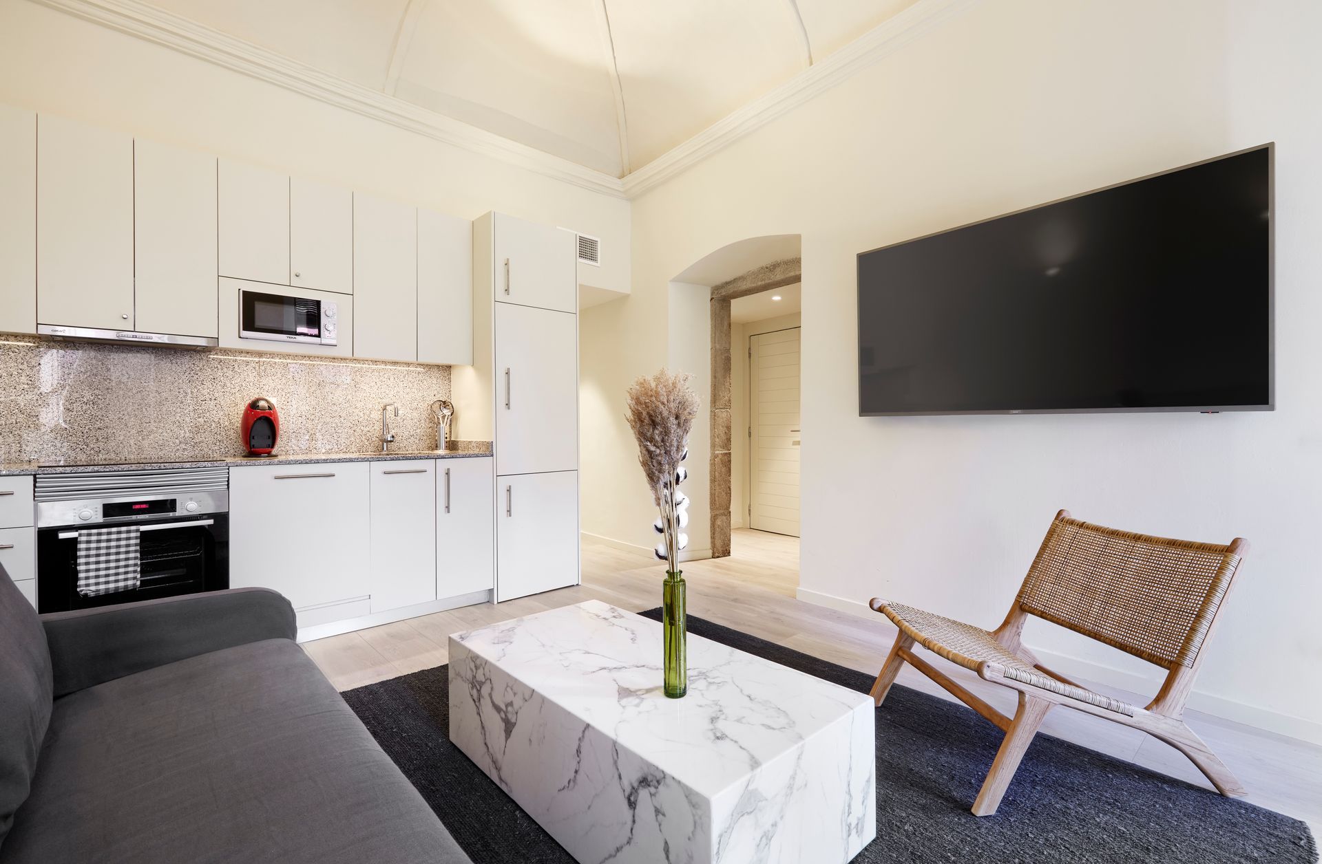 A living room with a couch , chair , coffee table and television.