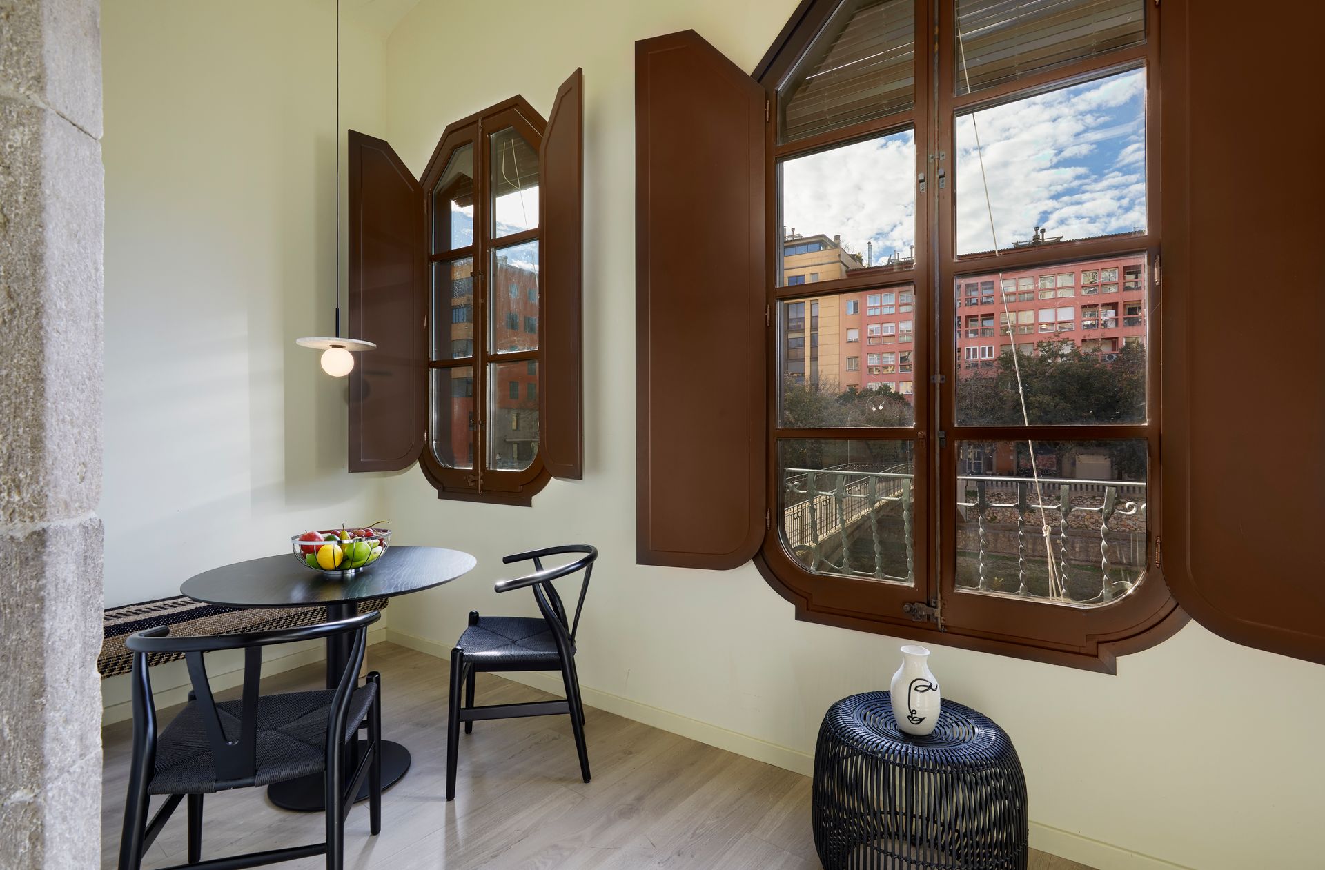 A dining room with a table and chairs and two windows