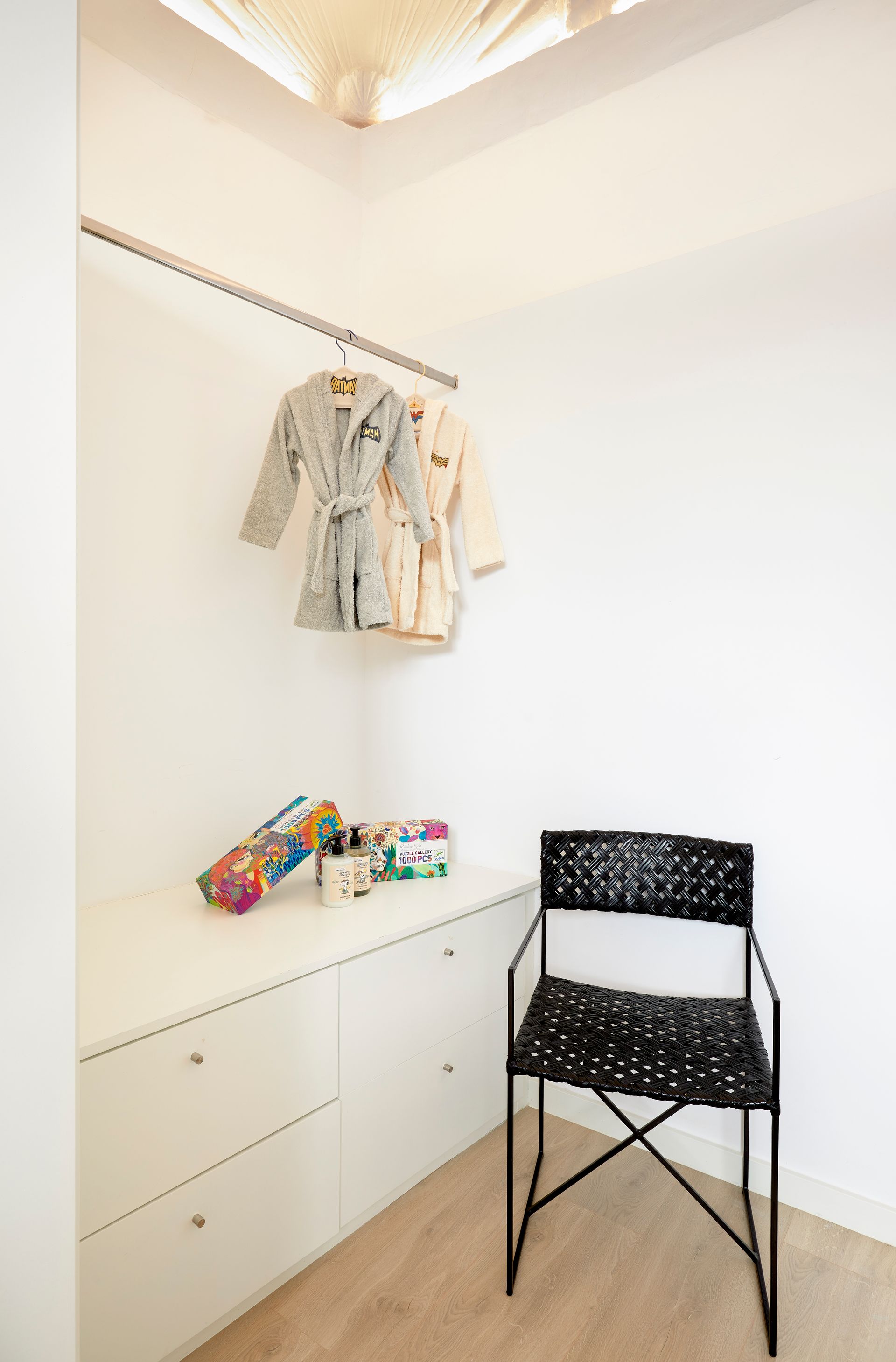 A closet with a chair and clothes hanging on a rack.