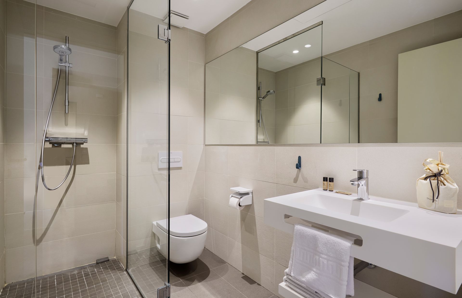 A bathroom with a toilet , sink , mirror and walk in shower.