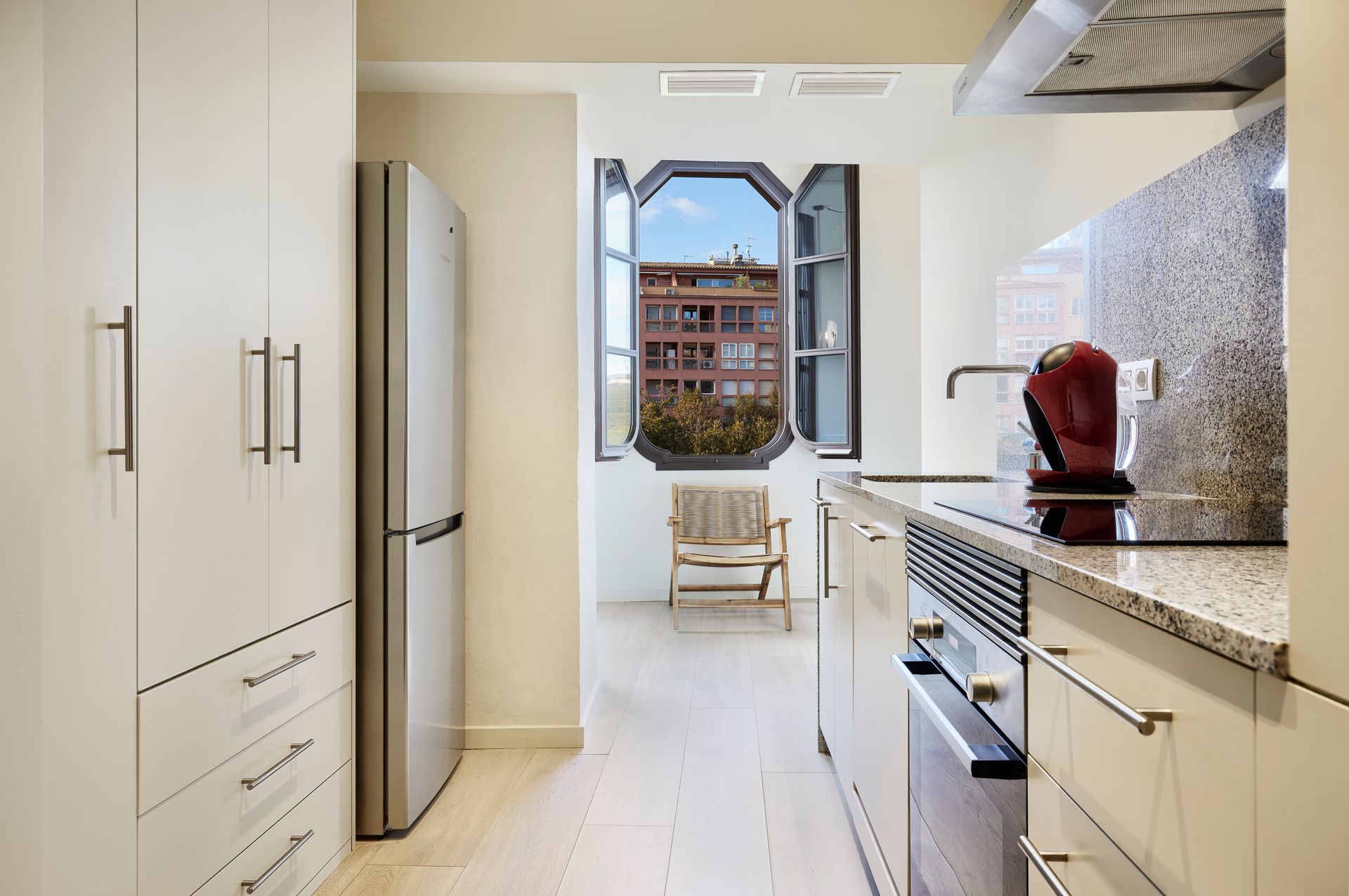 A kitchen with a large window and a red coffee maker