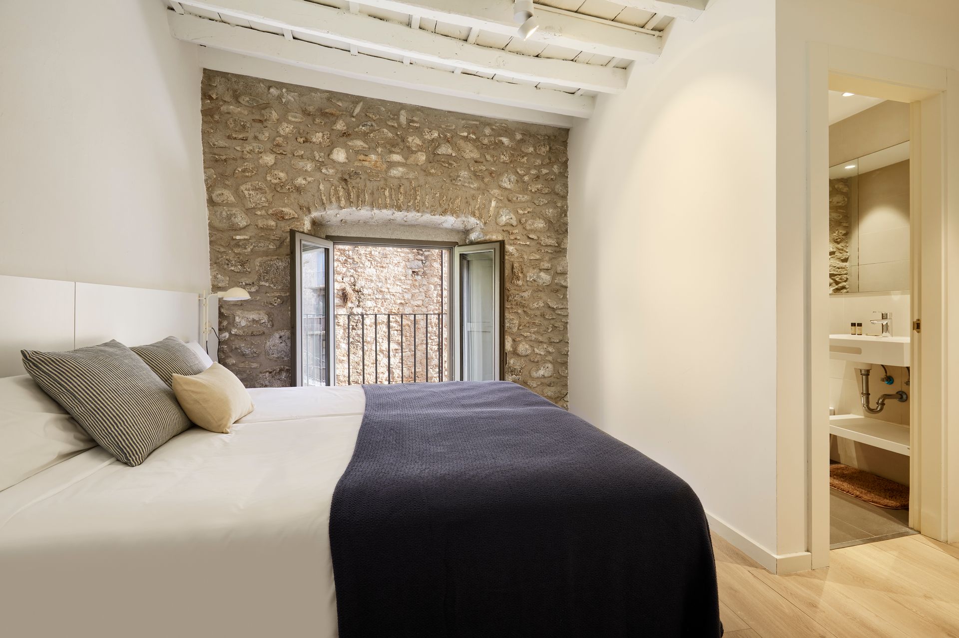 A bedroom with a large bed and a stone wall.