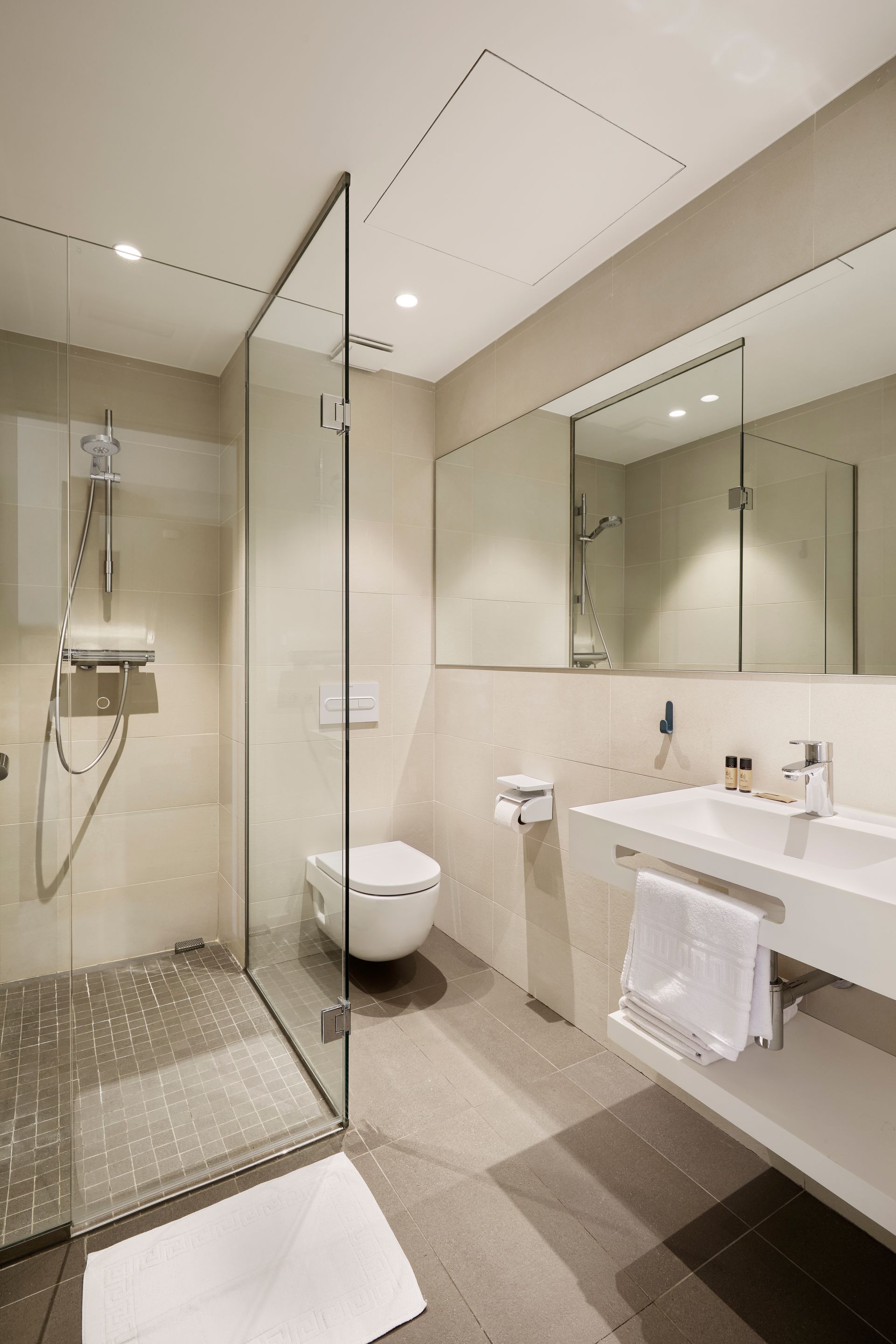 A bathroom with a toilet , sink , mirror and walk in shower.