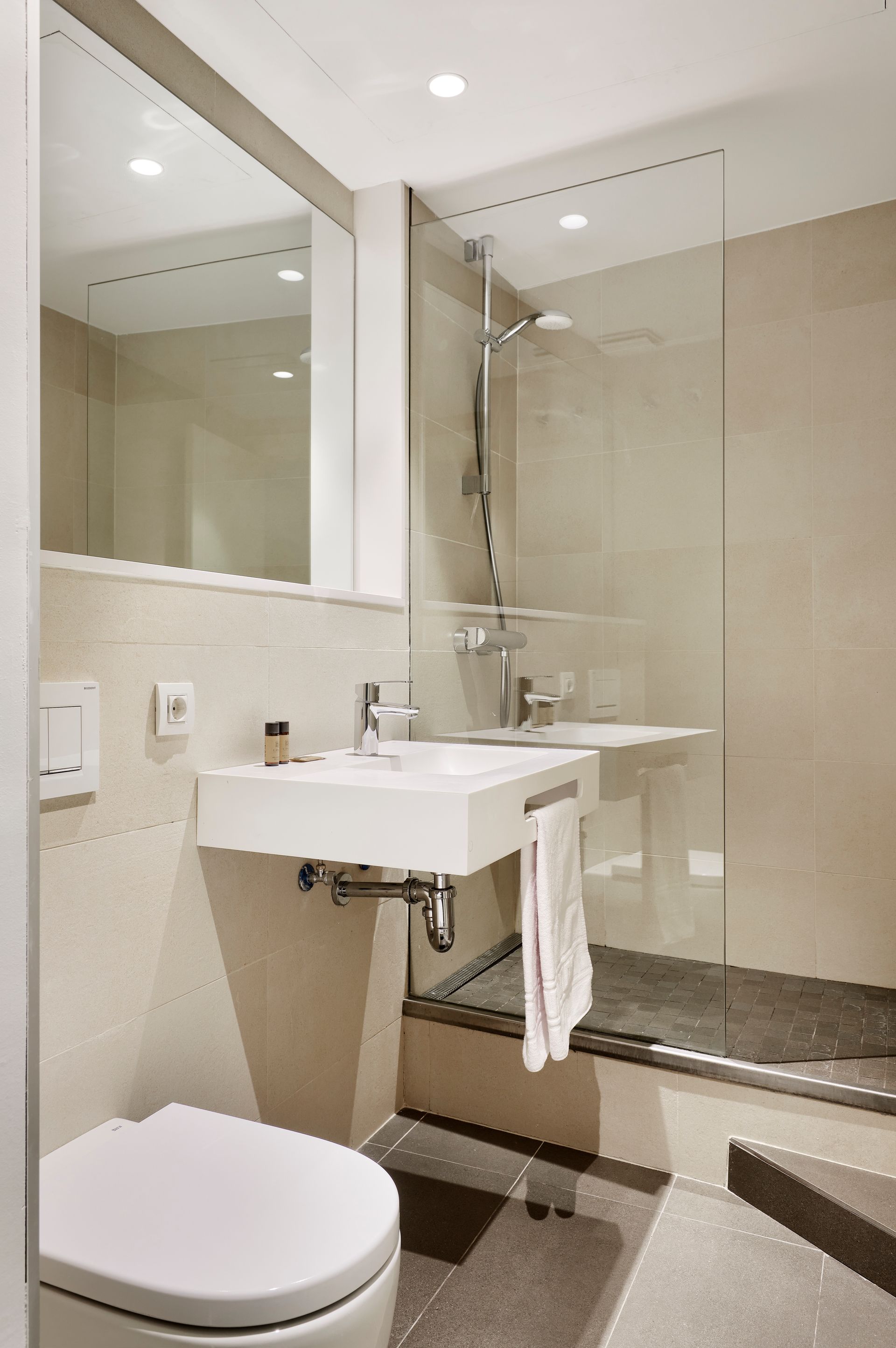 A bathroom with a toilet , sink , mirror and shower.