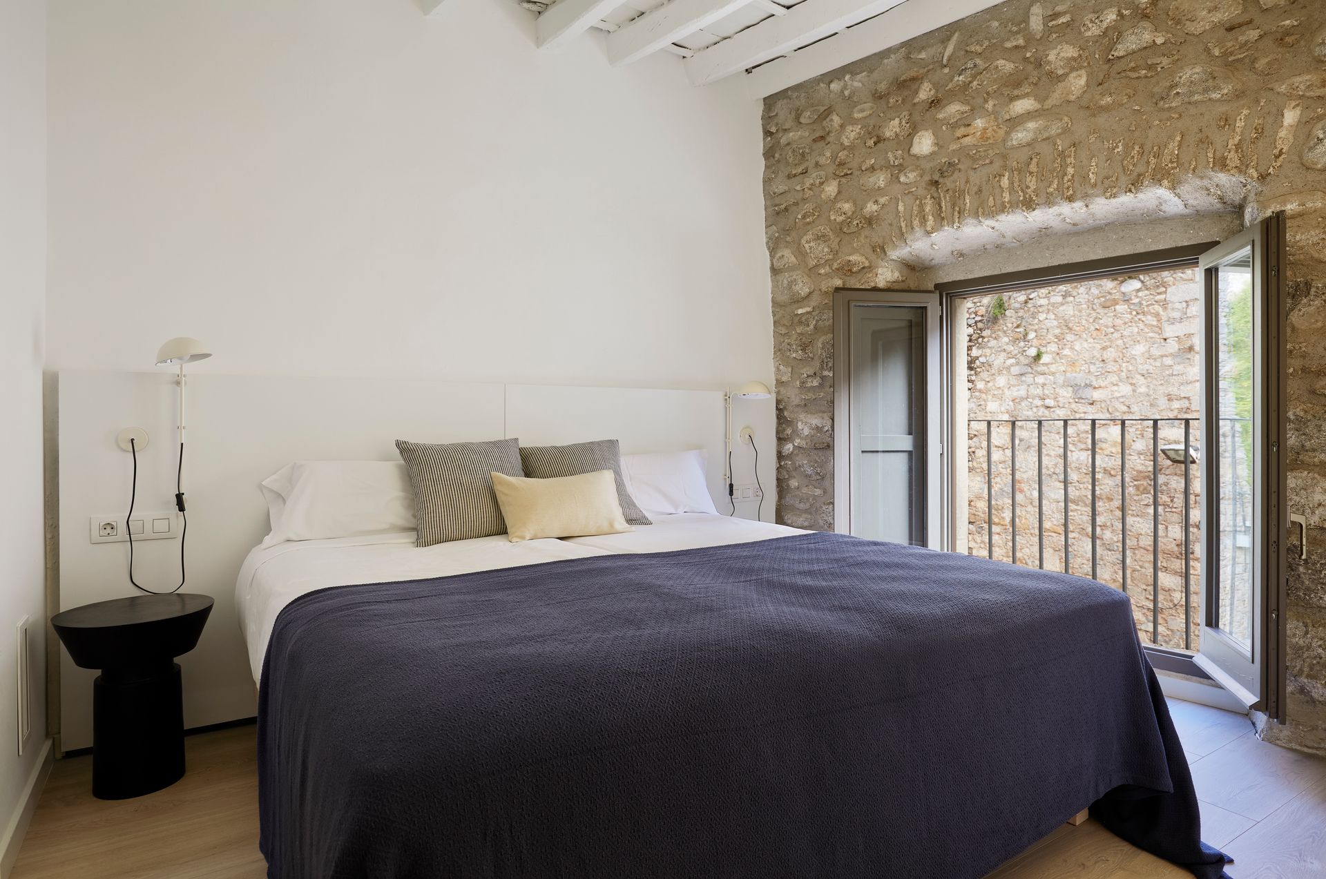 A bedroom with a large bed and a stone wall.