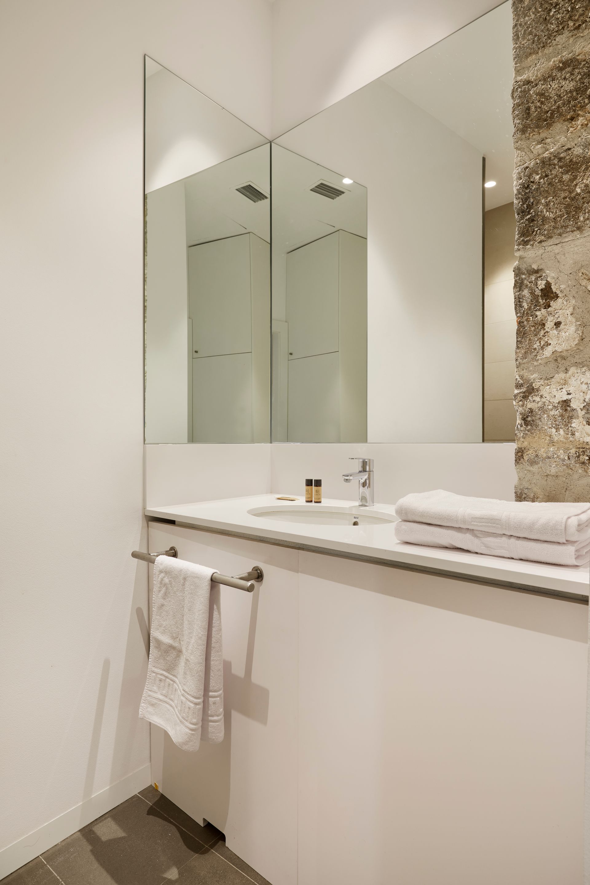 A bathroom with a sink , mirror and towels on the counter.